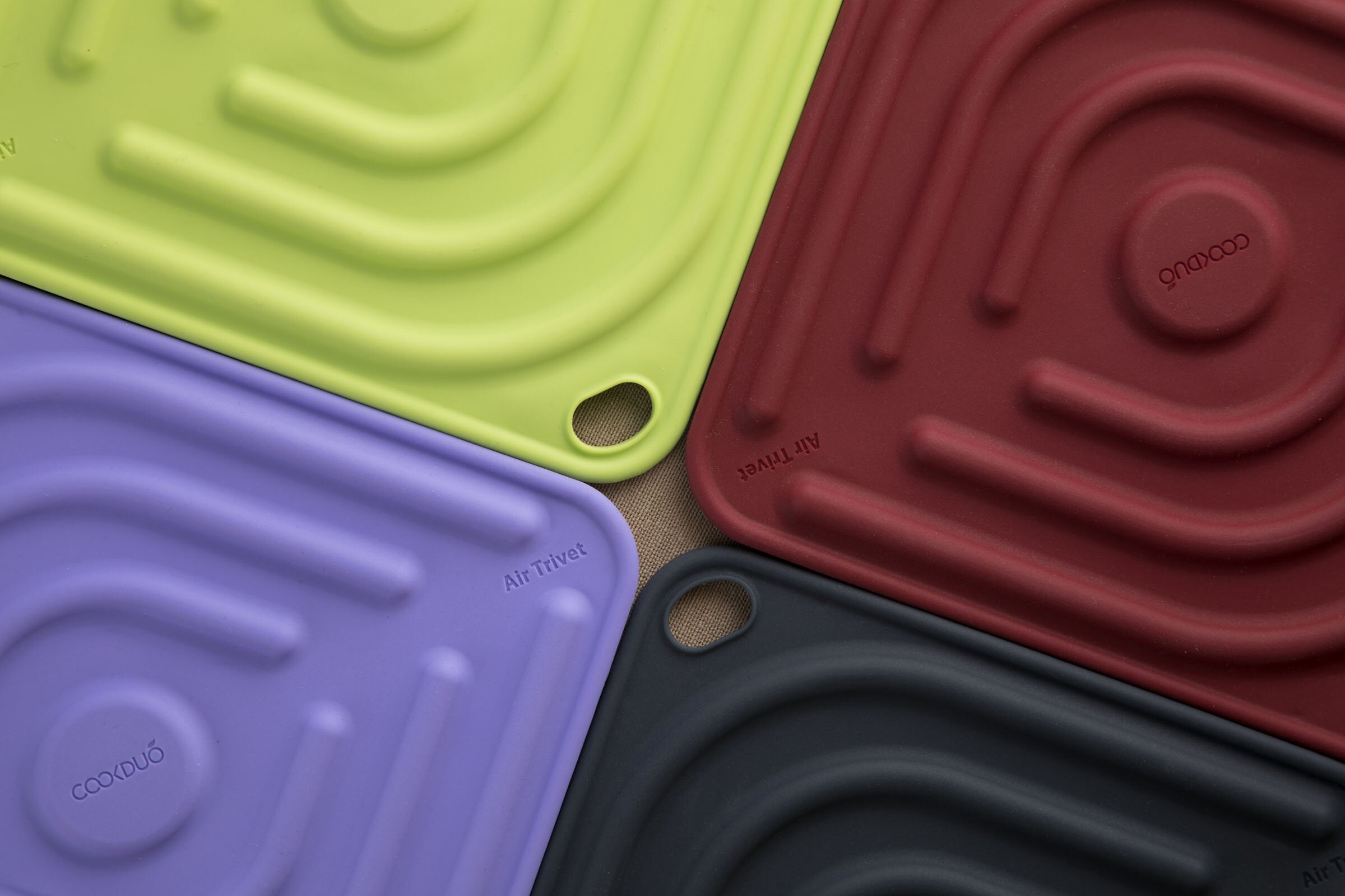 Top-down macro of four Cookduo Air Trivets meeting at the corners, showing the ribbed silicone channel pattern and Air Trivet wordmark