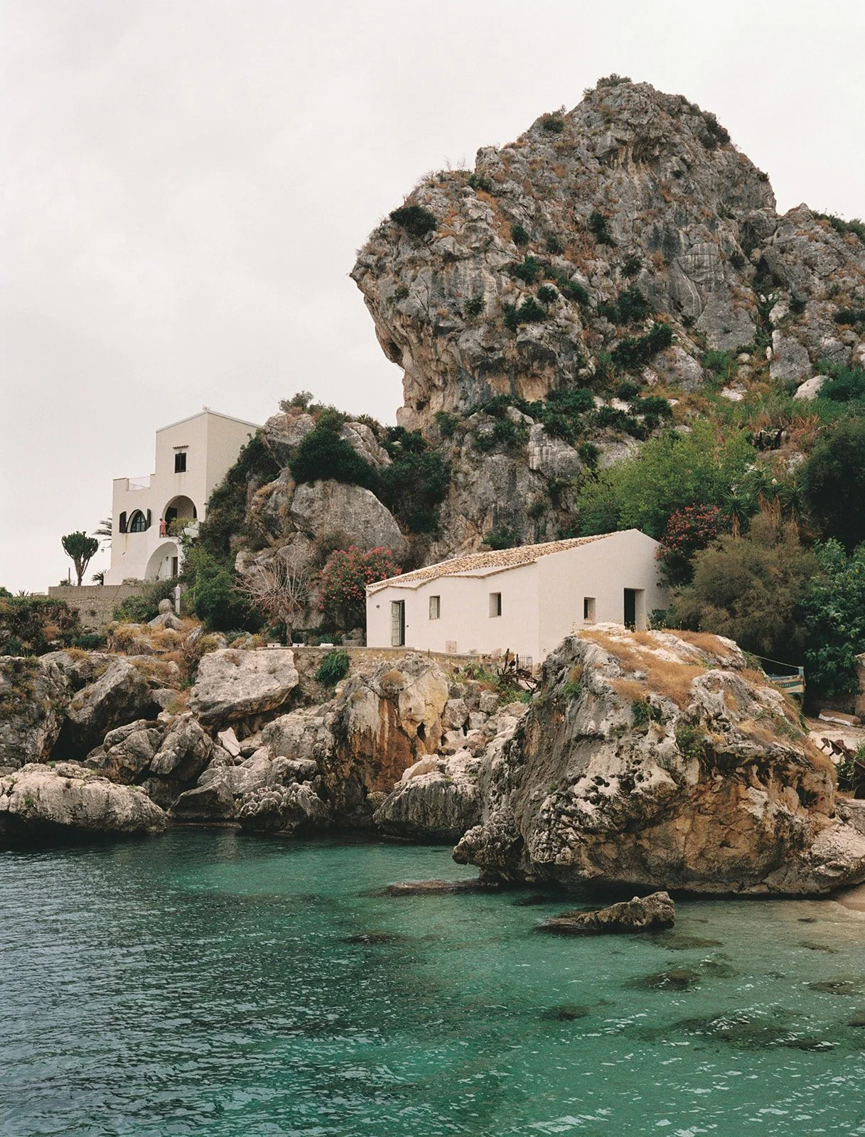 Historic Sicilian fishing village buildings viewed from the water, now used as a unique wedding venue.