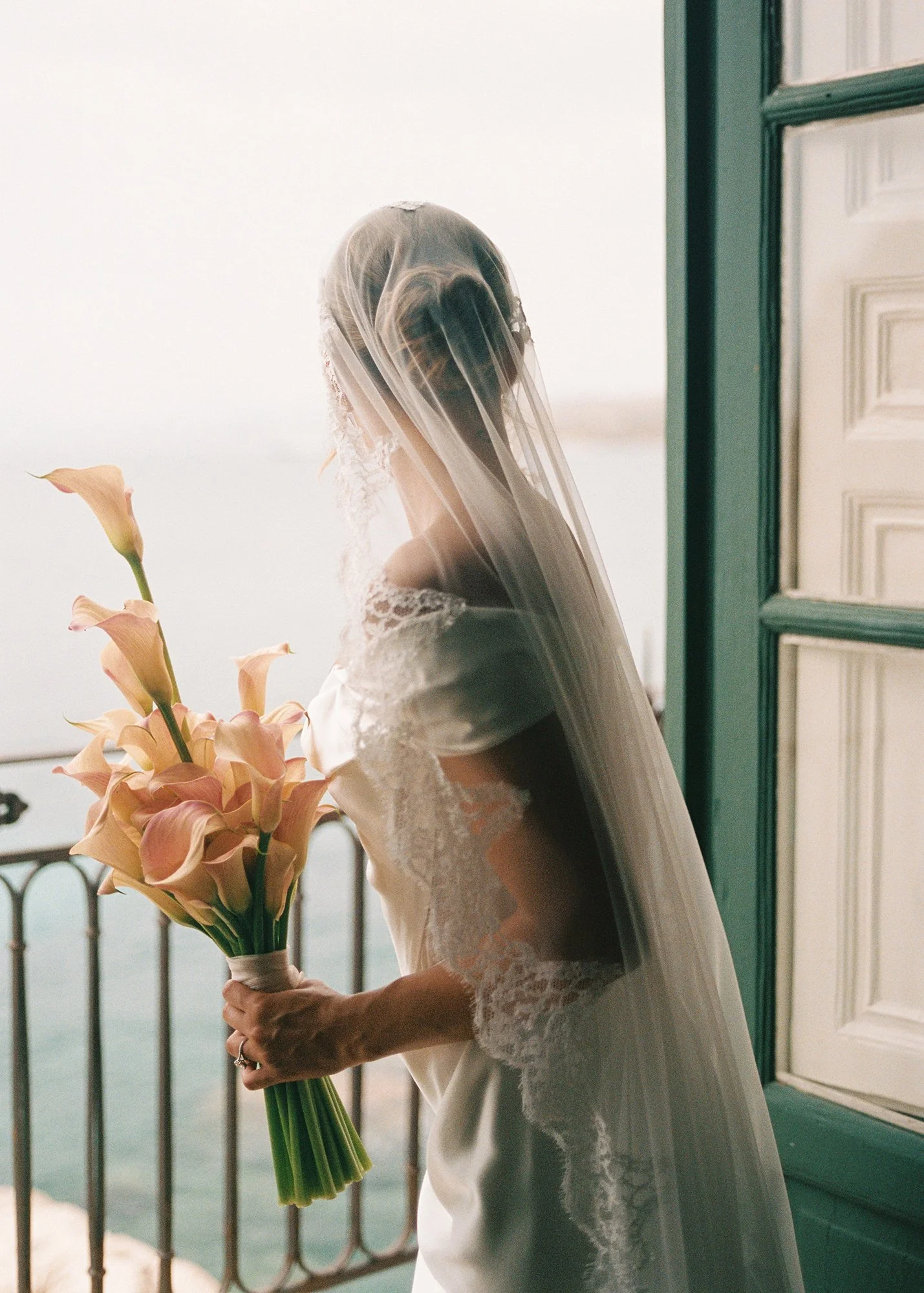 Vivienne westwood wedding dress with Mantilla veil and pink and white calla lilies at wedding at Tonnara di Scopello