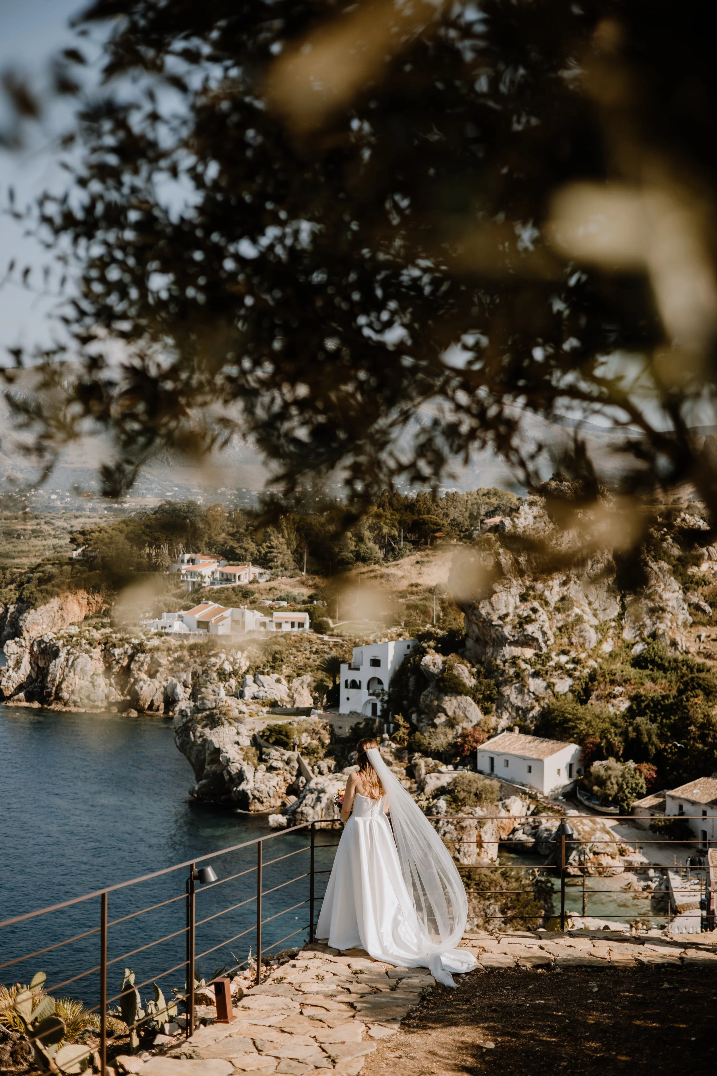 Bride gazing out over the Mediterranean at Torre di Scopello wedding venue, Sicily.