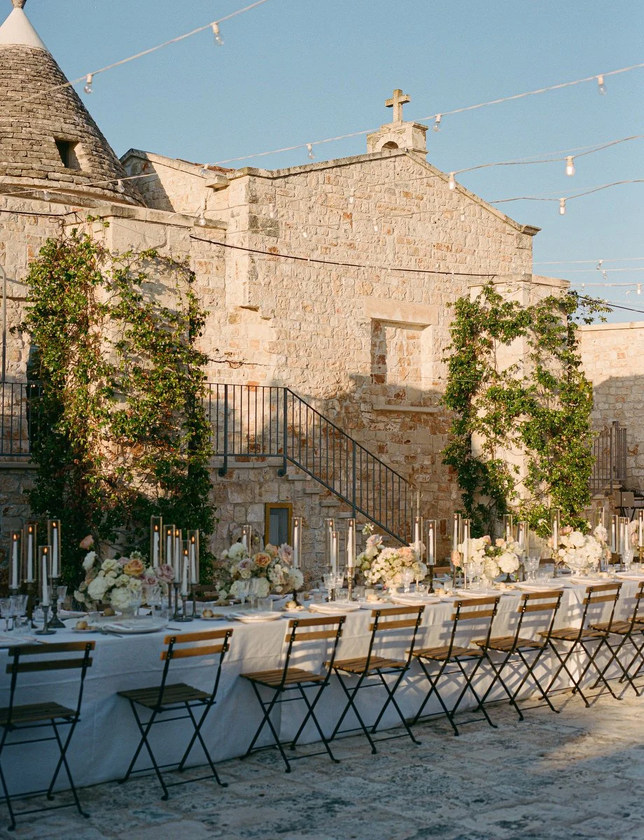 Close-up of an elegantly styled wedding reception table at a limestone masseria in the Valle d'Itria, Puglia.
