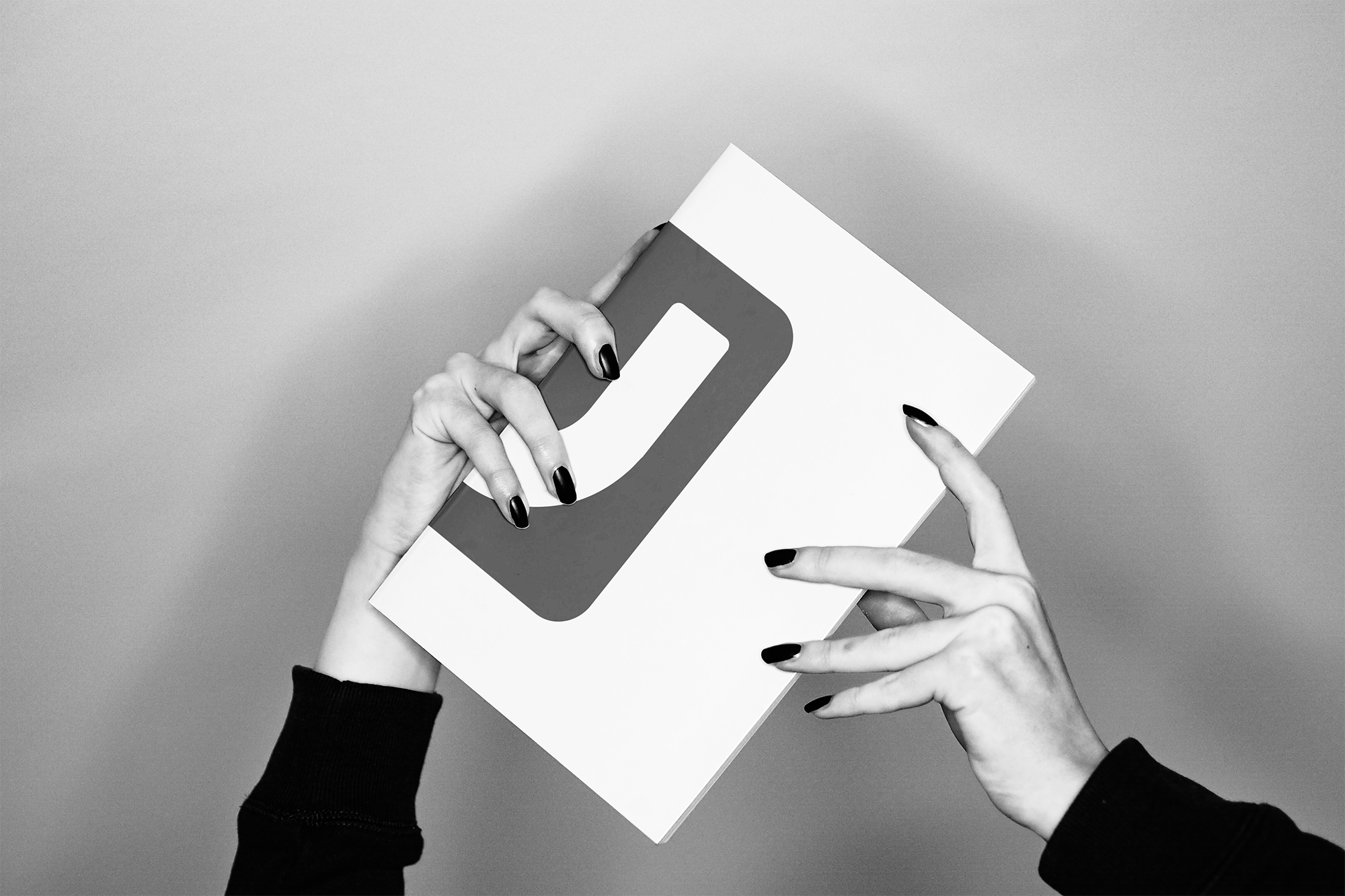 Mãos femininas com unhas pretas segurando uma caixa de papelão com o logotipo da LinkedIn em destaque