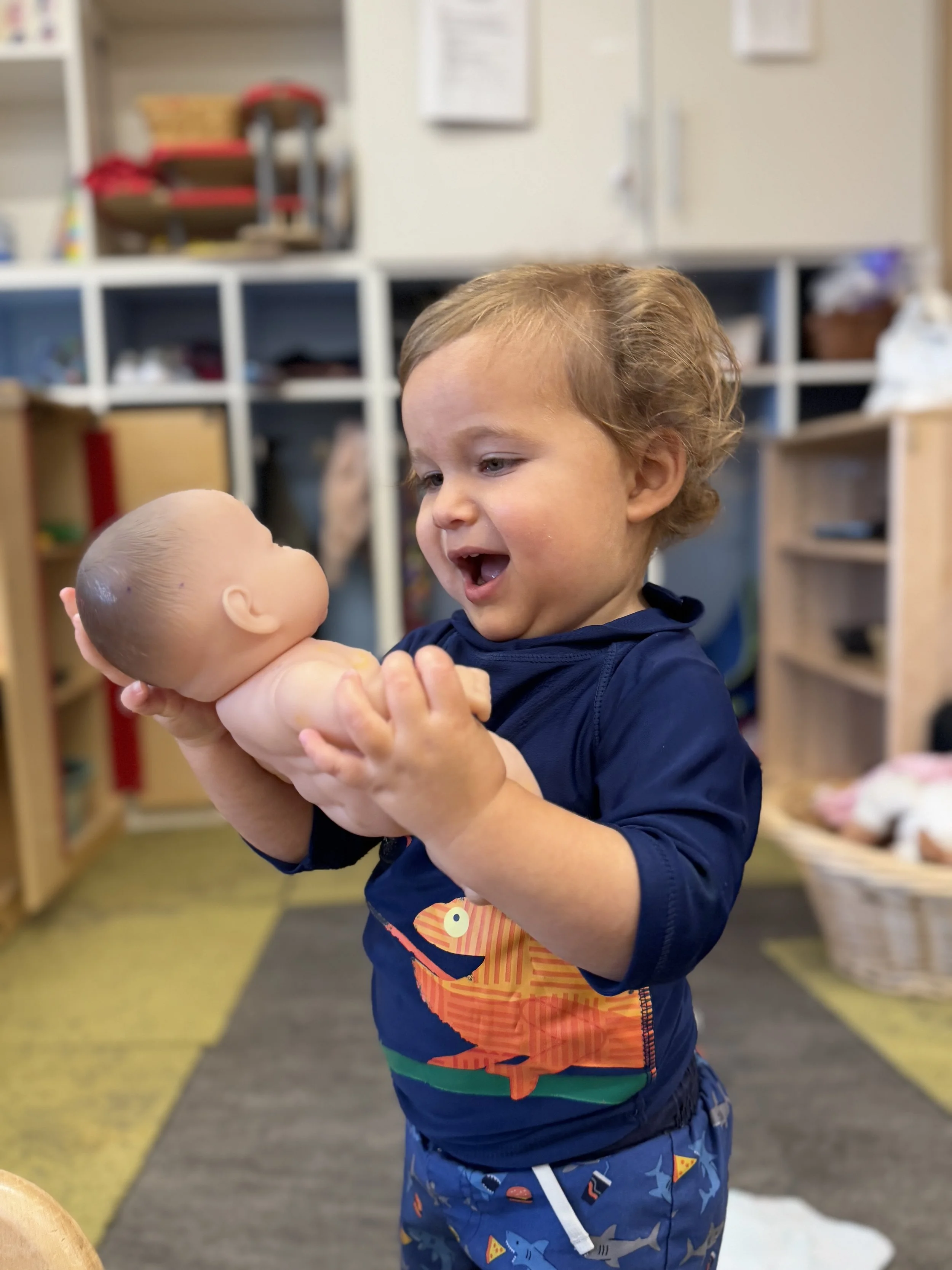 ECC toddler smiles at doll