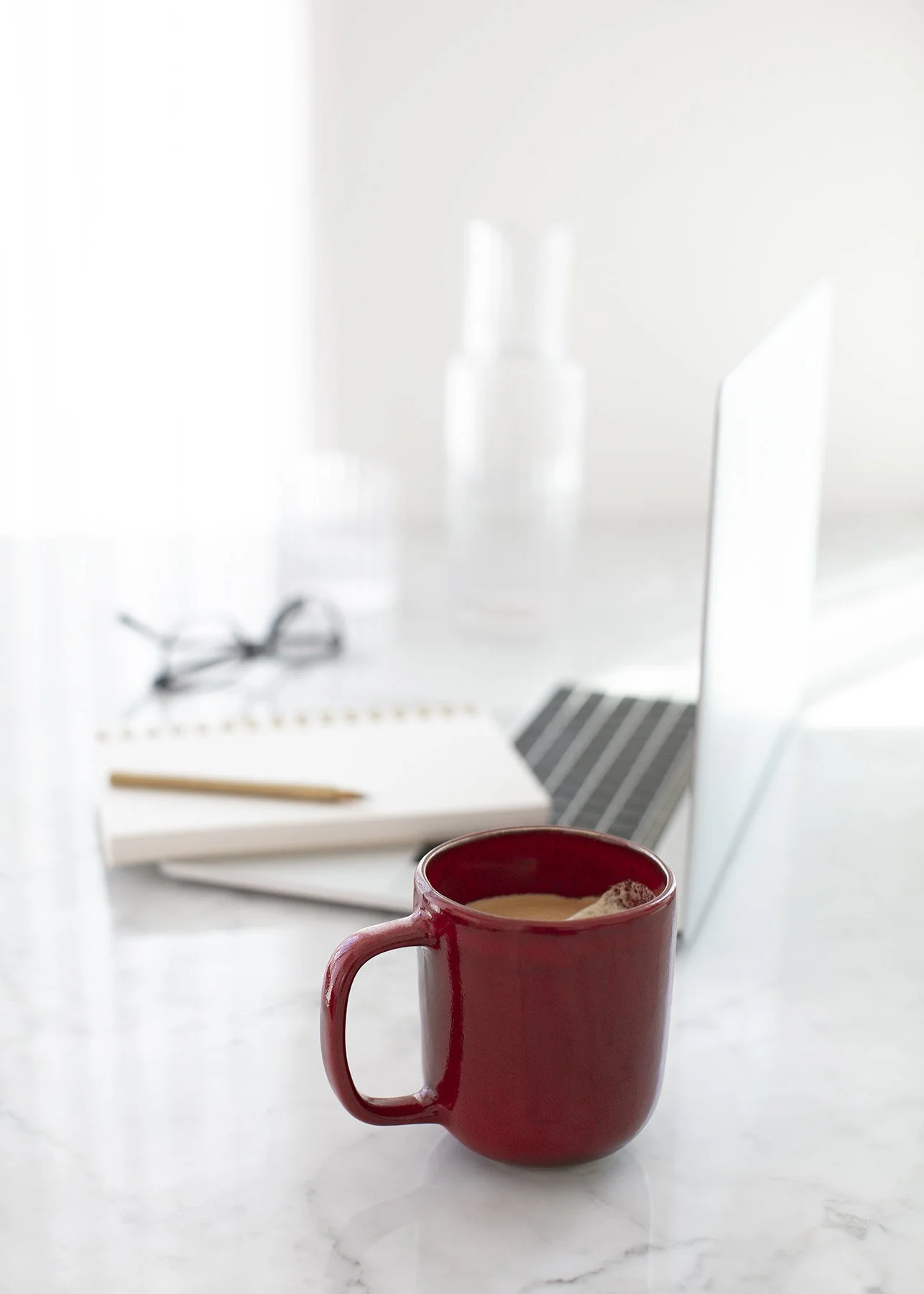 cup of coffee in a red cup and a laptop background