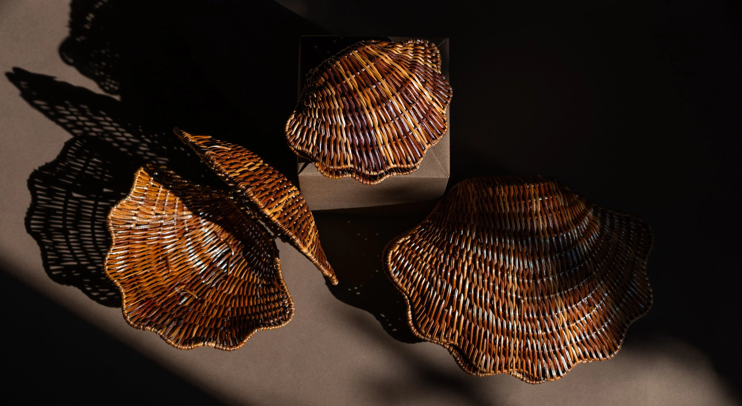 Vintage set of 3 nesting lacquered rattan sea shells with tied cane hinges/ Features: Can rest on flattened section of hinge or on circular braided base/ Color: Walnut/ Dims: Large 7.5” H x 10” W/ Medium 6” H x 8” W/ Small 5” H x 6” W