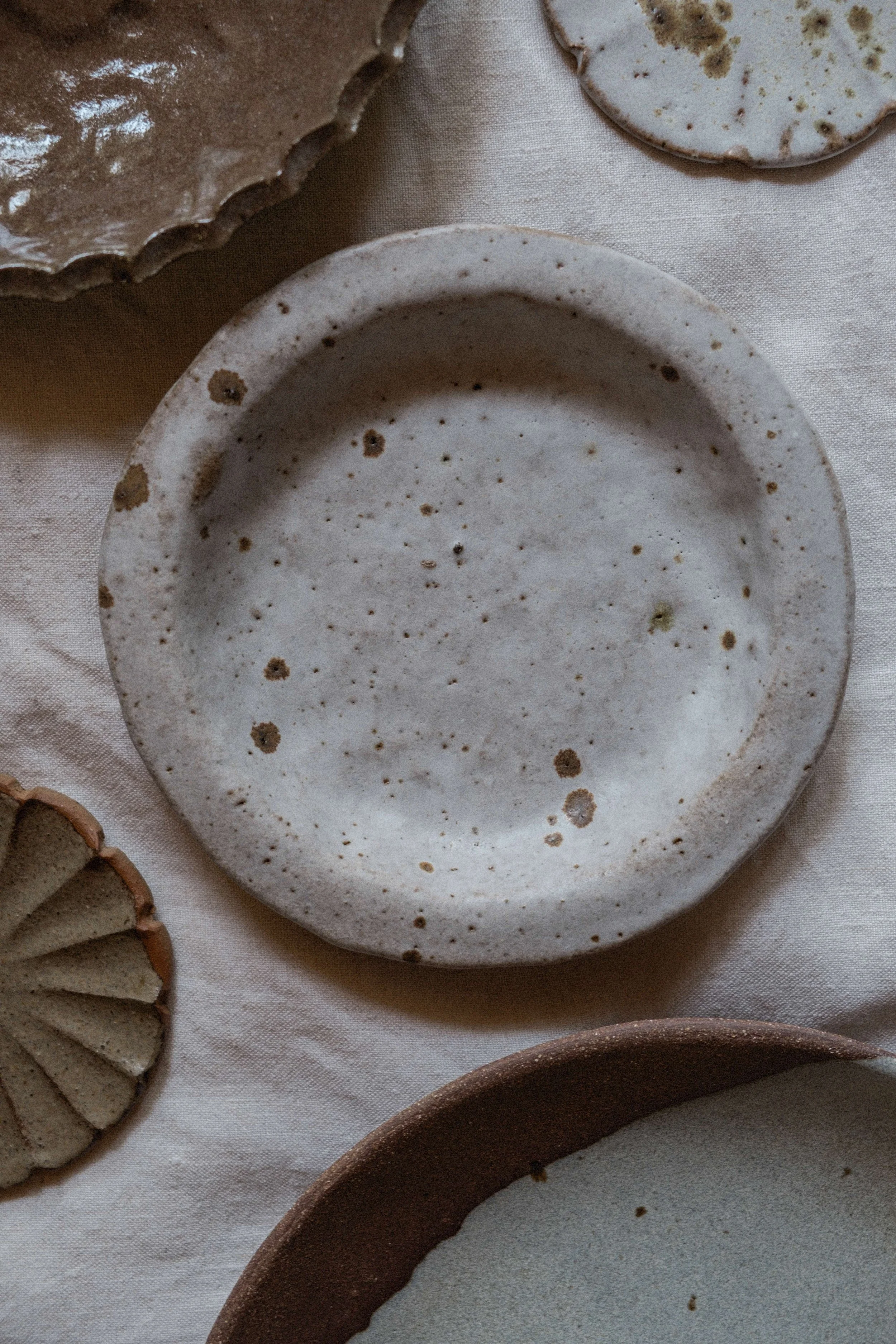 PETITE ASSIETTE À REBORDS EN TERRE GLANÉE ET GRÈS ROUGE / D 15 CM / ÉMAIL BLANC MAT / MOUCHETÉ