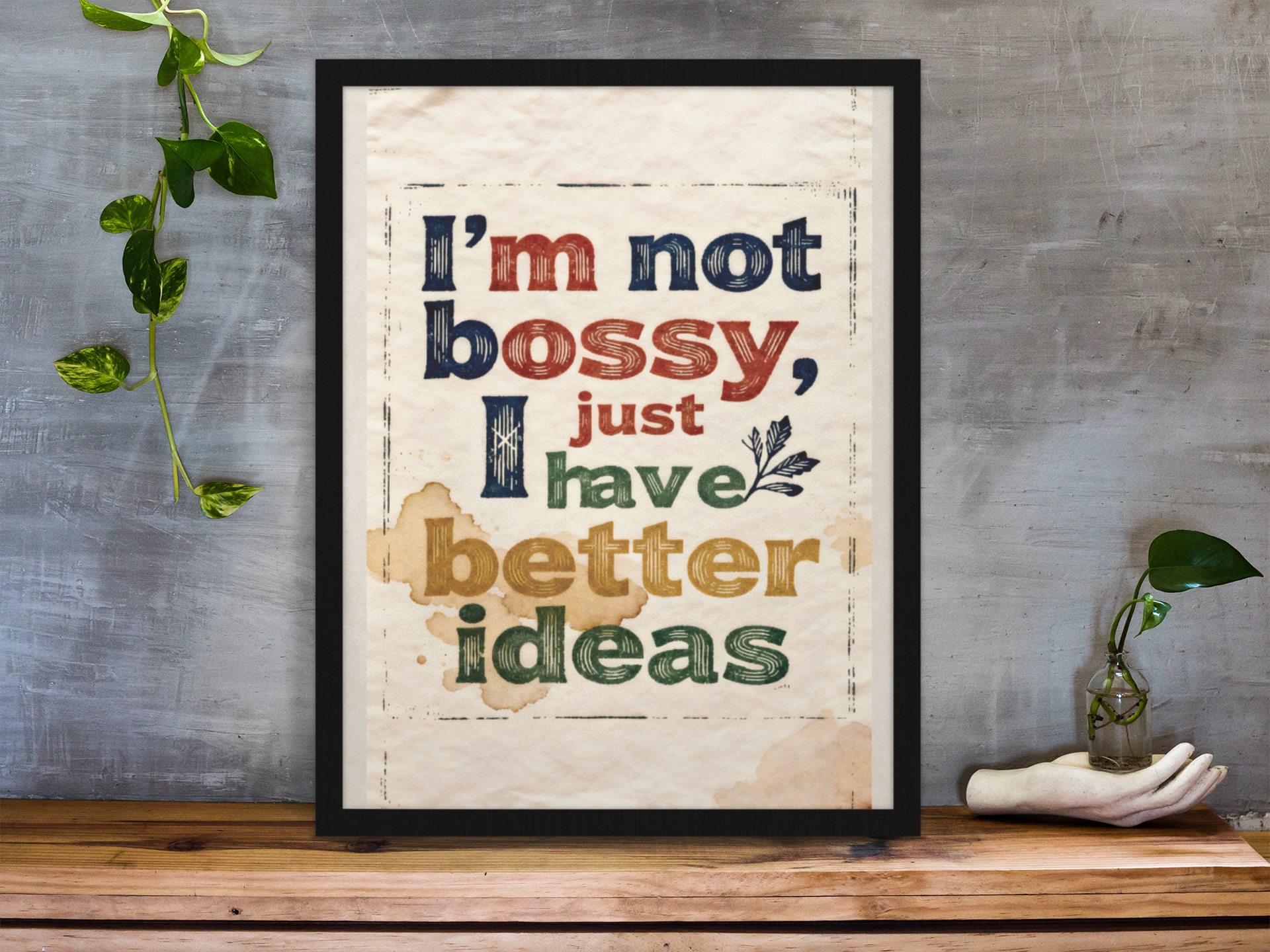 framed-art-print-standing-on-a-wooden-desk-against-a-concrete-wall-near-a-hand-decoration-a10403.png