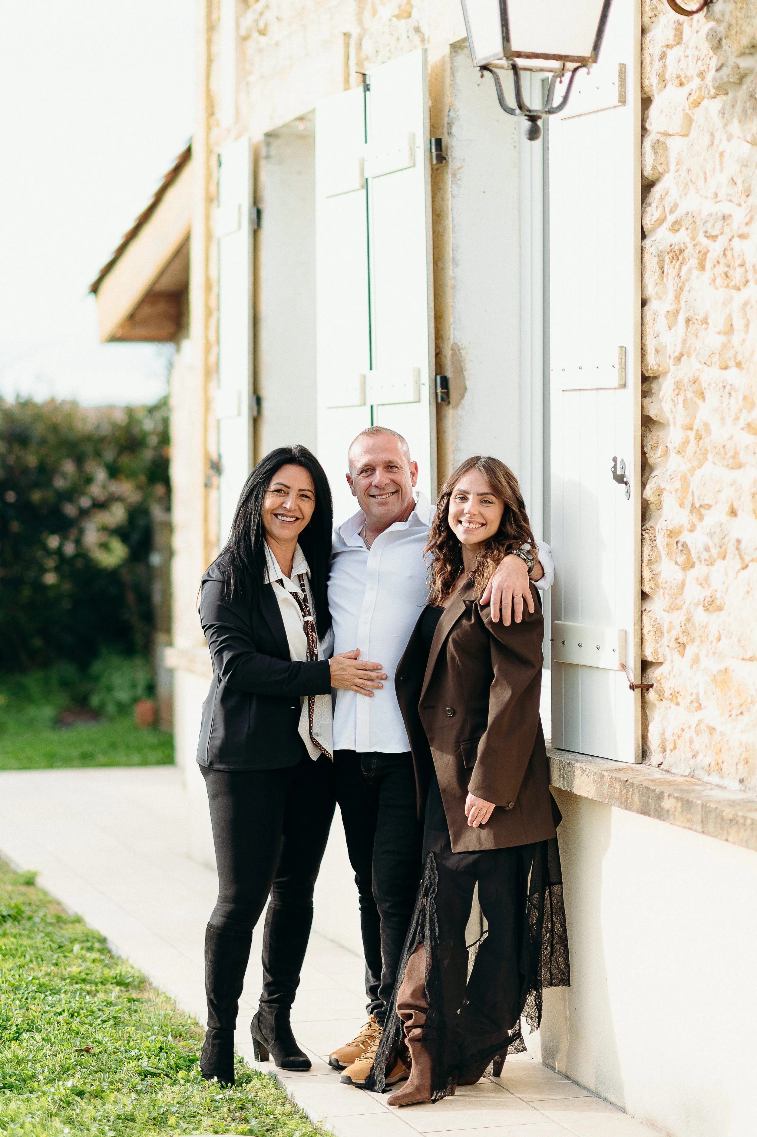 Séance photo famille à Bordeaux avec un couple adulte et un membre de la famille devant la maison