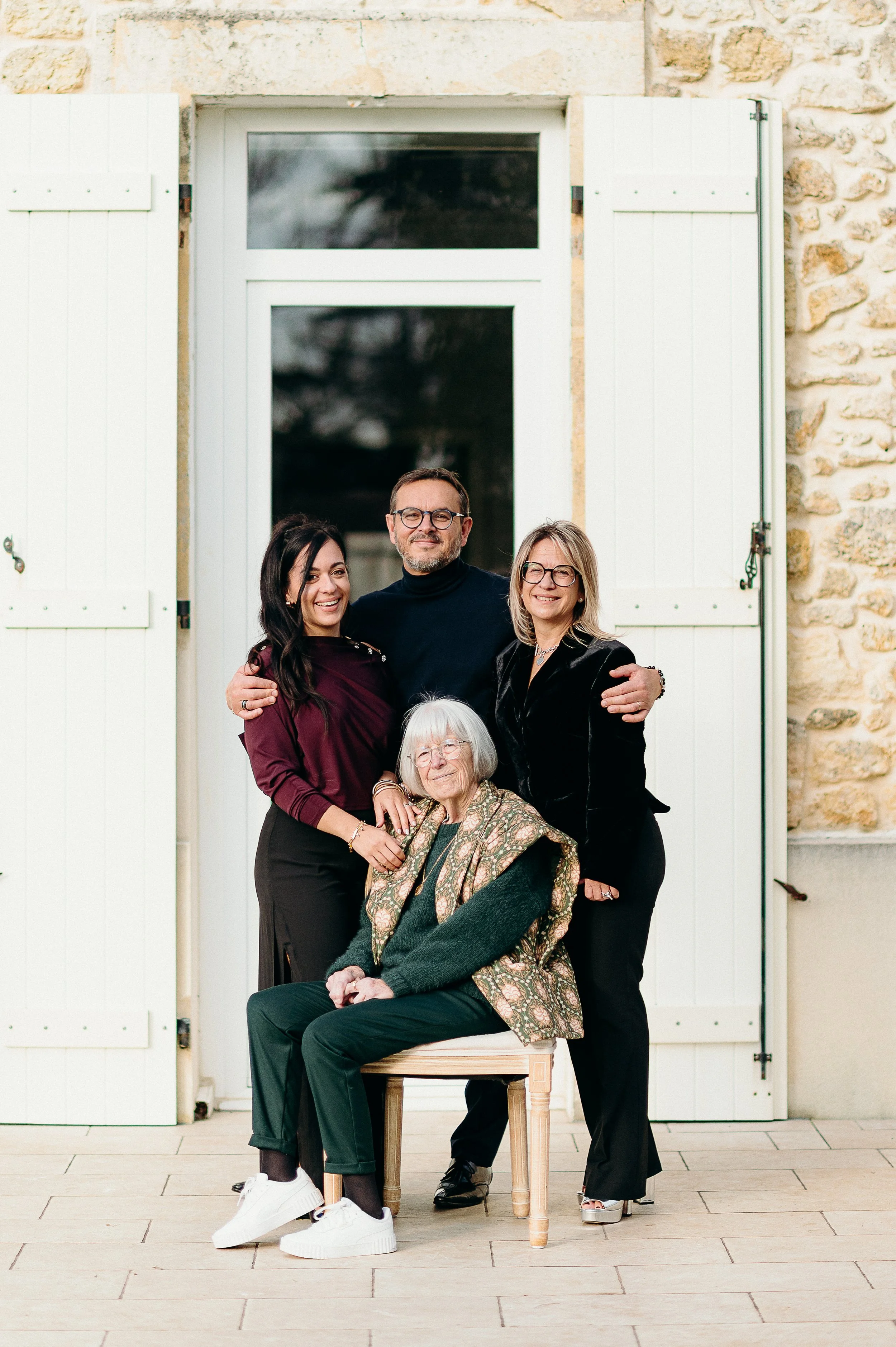 Séance photo famille à Bordeaux avec plusieurs générations réunies autour de la grand-mère devant la maison familiale