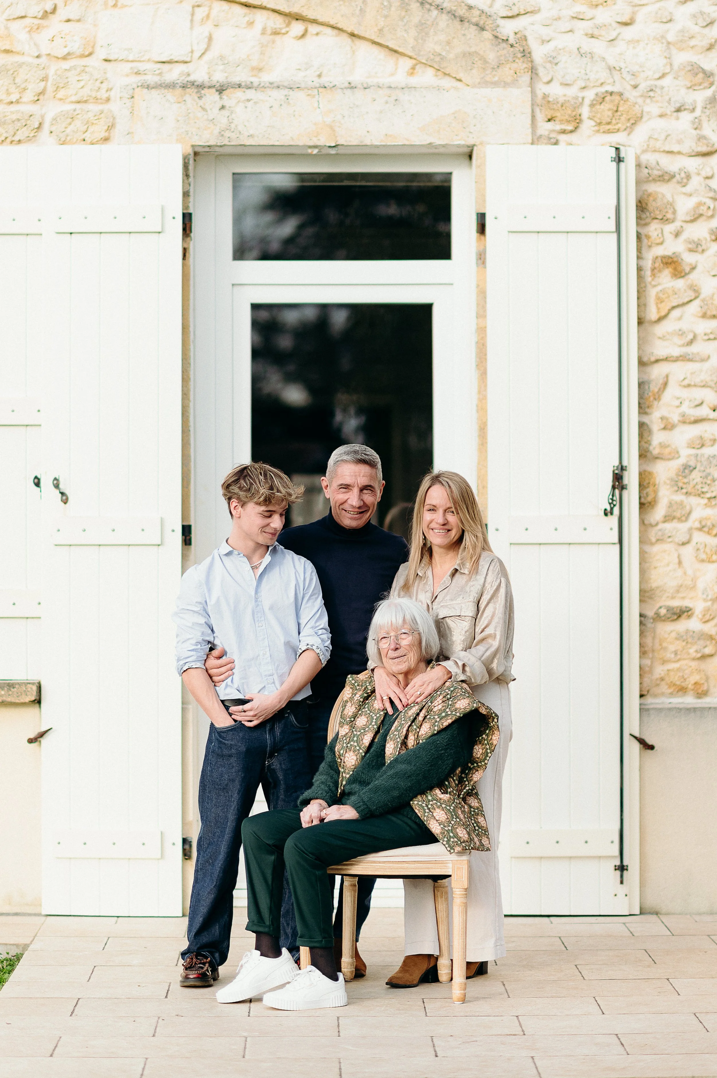 Photographe famille à Bordeaux réalisant un portrait intergénérationnel devant la maison familiale