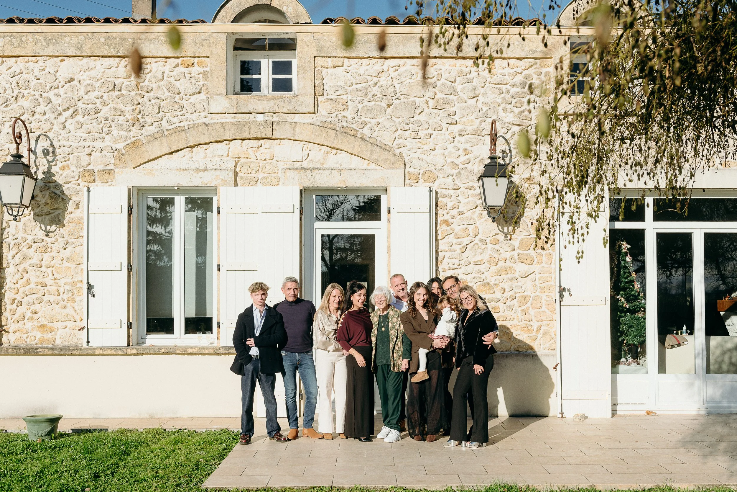 Photos de réunion de famille à Bordeaux avec plusieurs générations réunies devant une maison en pierre