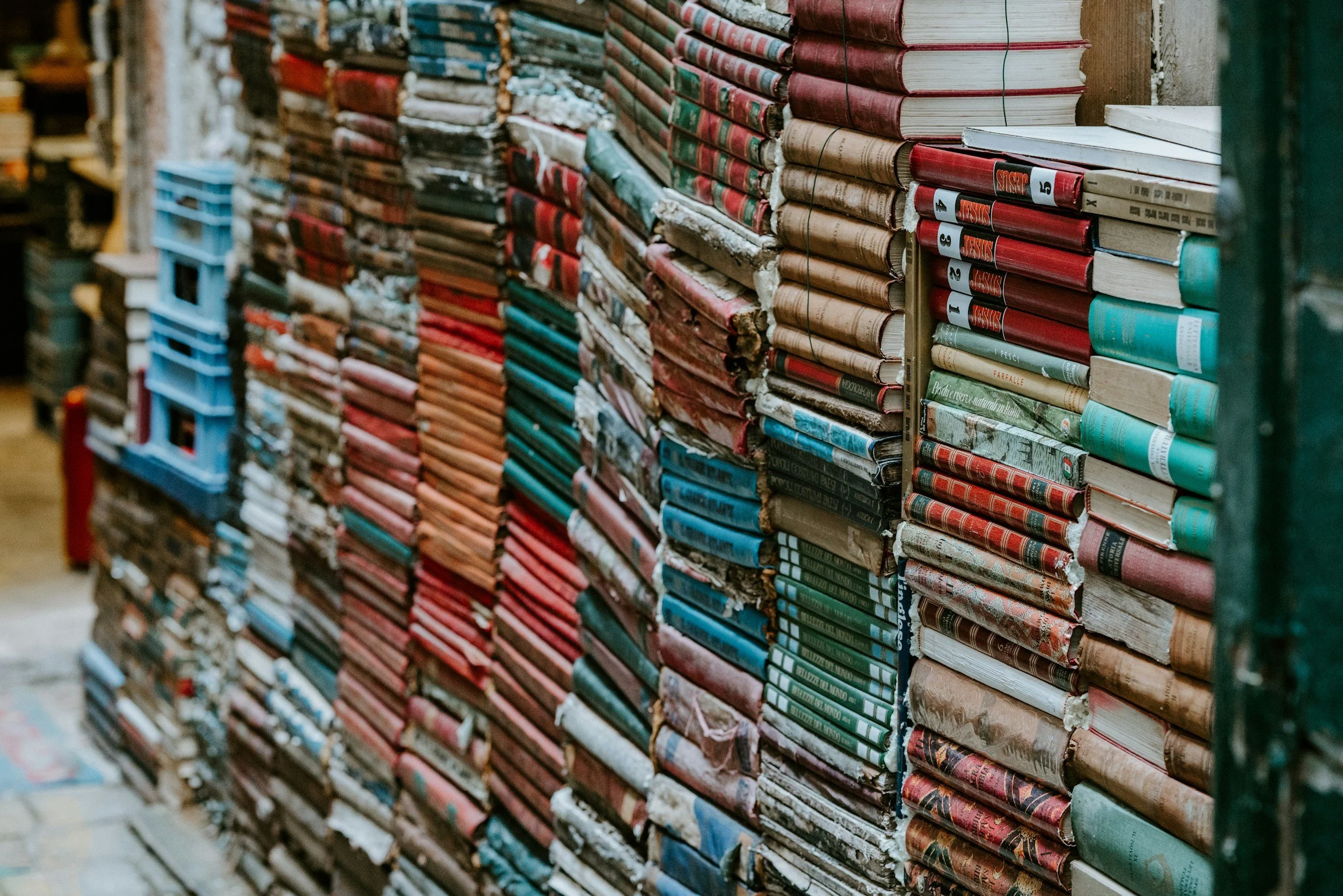 A row of colorful, differently sized books stacked along a wall — representing the many programs, projects, and funding streams within a nonprofit, and the importance of smart financial allocations to keep every chapter of the organization supported.