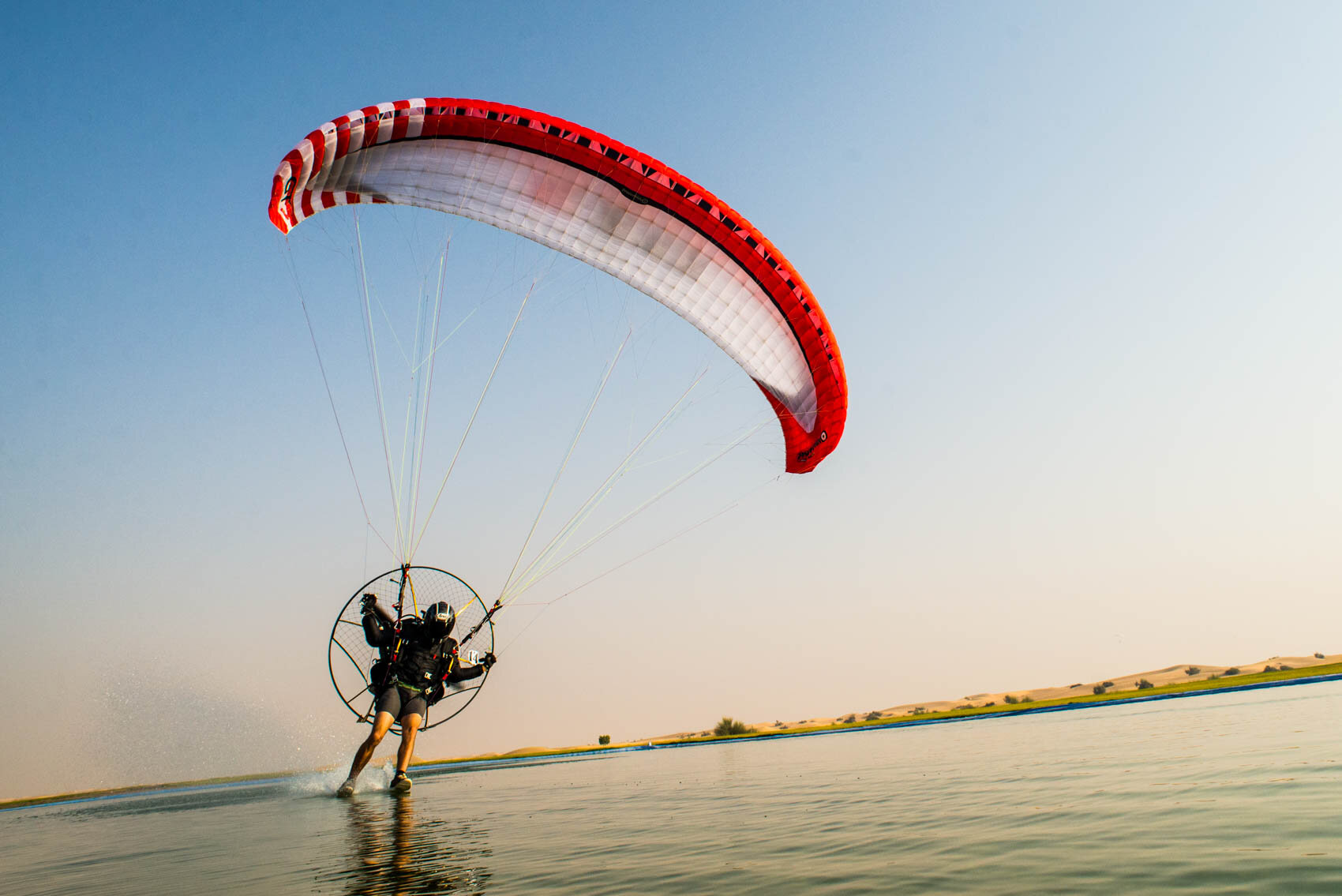 stock-photo-a-paramotor-pilot-demonstrating-a-foot-drag-through-water-while-flying-in-the-dubai-desert-246733899.jpg