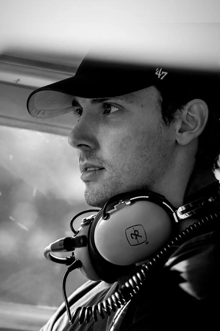 Black and white photo of a man wearing a cap and headphones, looking thoughtful.