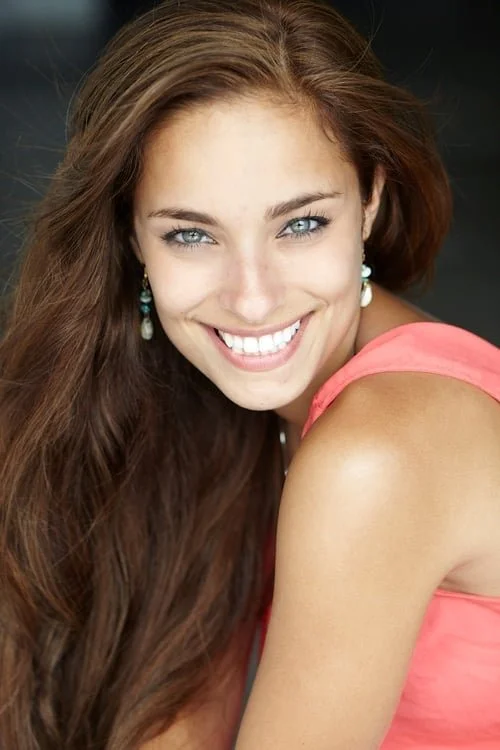 Smiling Kristen StephensonPino with long hair and earrings wearing a pink top.