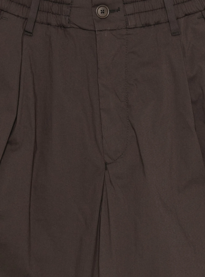 Drykorn CHASY pleated trousers in dark brown with elastic waistband, belt loops, and stretch cotton blend.
