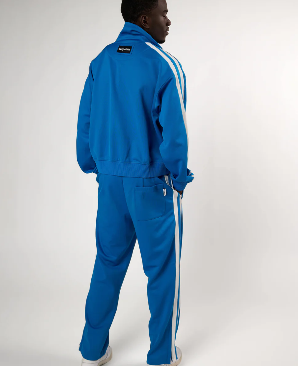 HOPEIUM track pants in cobalt with side stripes, elastic waistband, and relaxed fit.