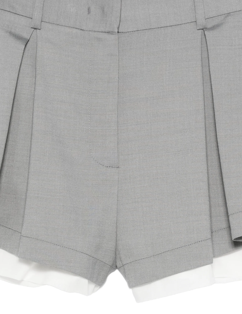 Grey pleated layered shorts by Tela, made in Italy with belt loops, button closure, and tailored details for modern style.