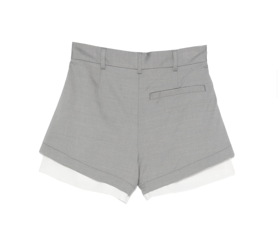 Grey pleated layered shorts by Tela, made in Italy with belt loops, button closure, and tailored details for modern style.