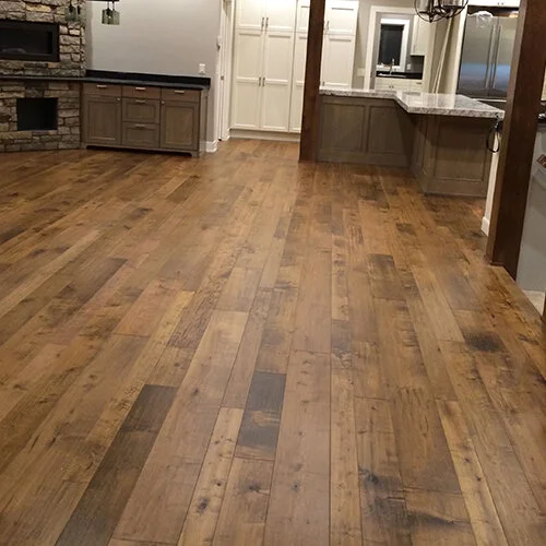Empty kitchen with hardwood flooring, white cabinets, granite countertops, and stainless steel appliances.