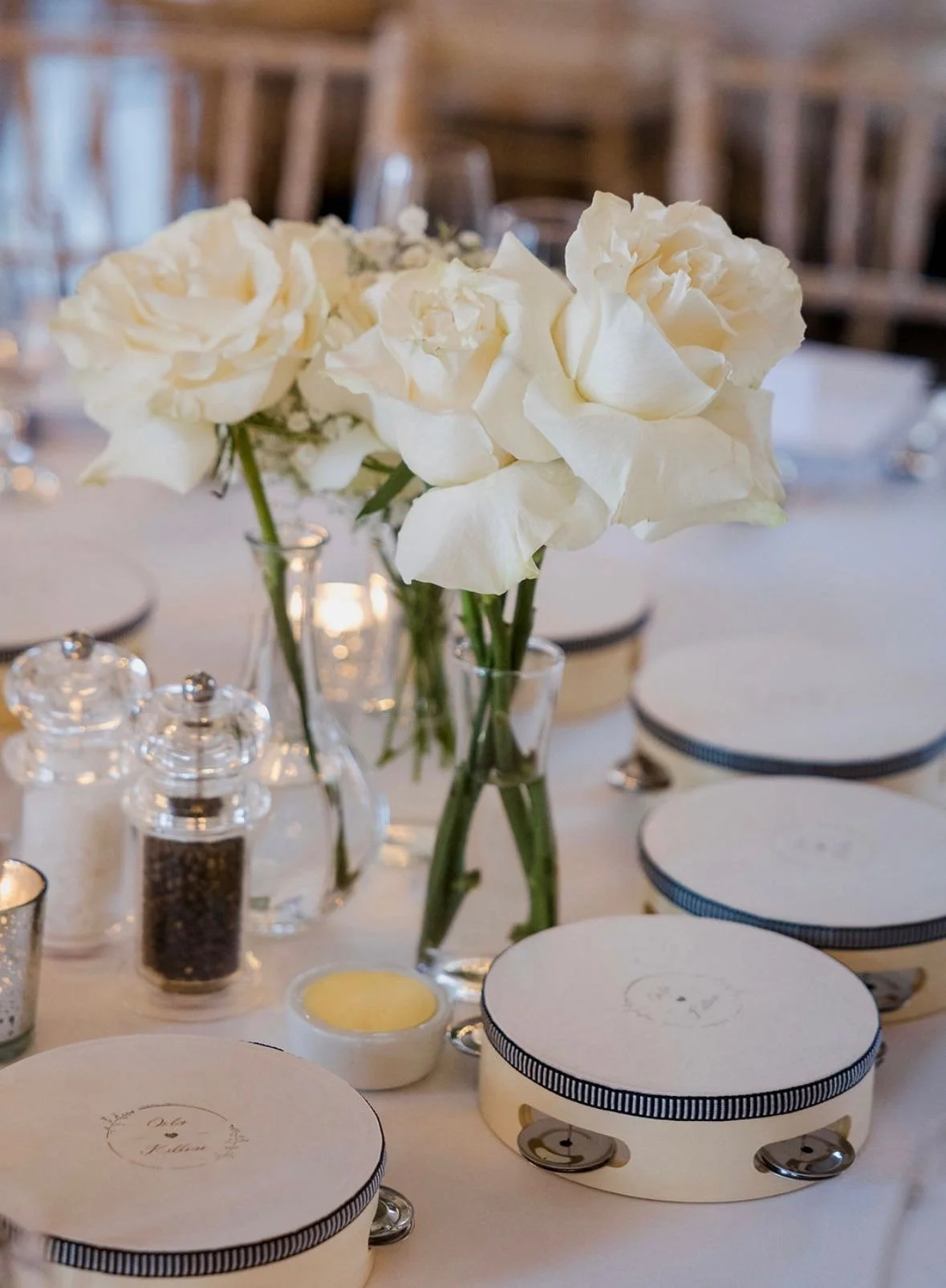 A floral centerpiece with white roses in a clear glass vase on a table set for a special event.