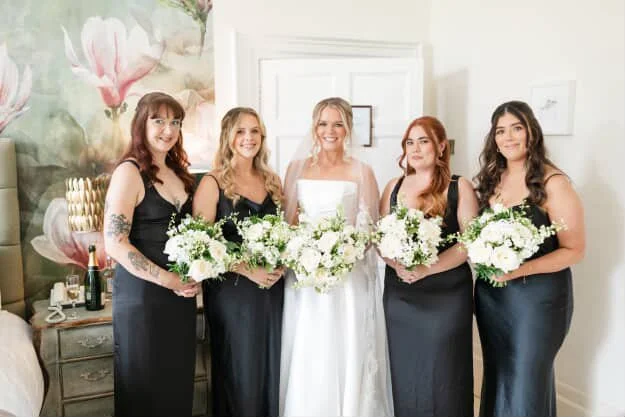 Bride with four bridesmaids holding bouquets in a decorated room