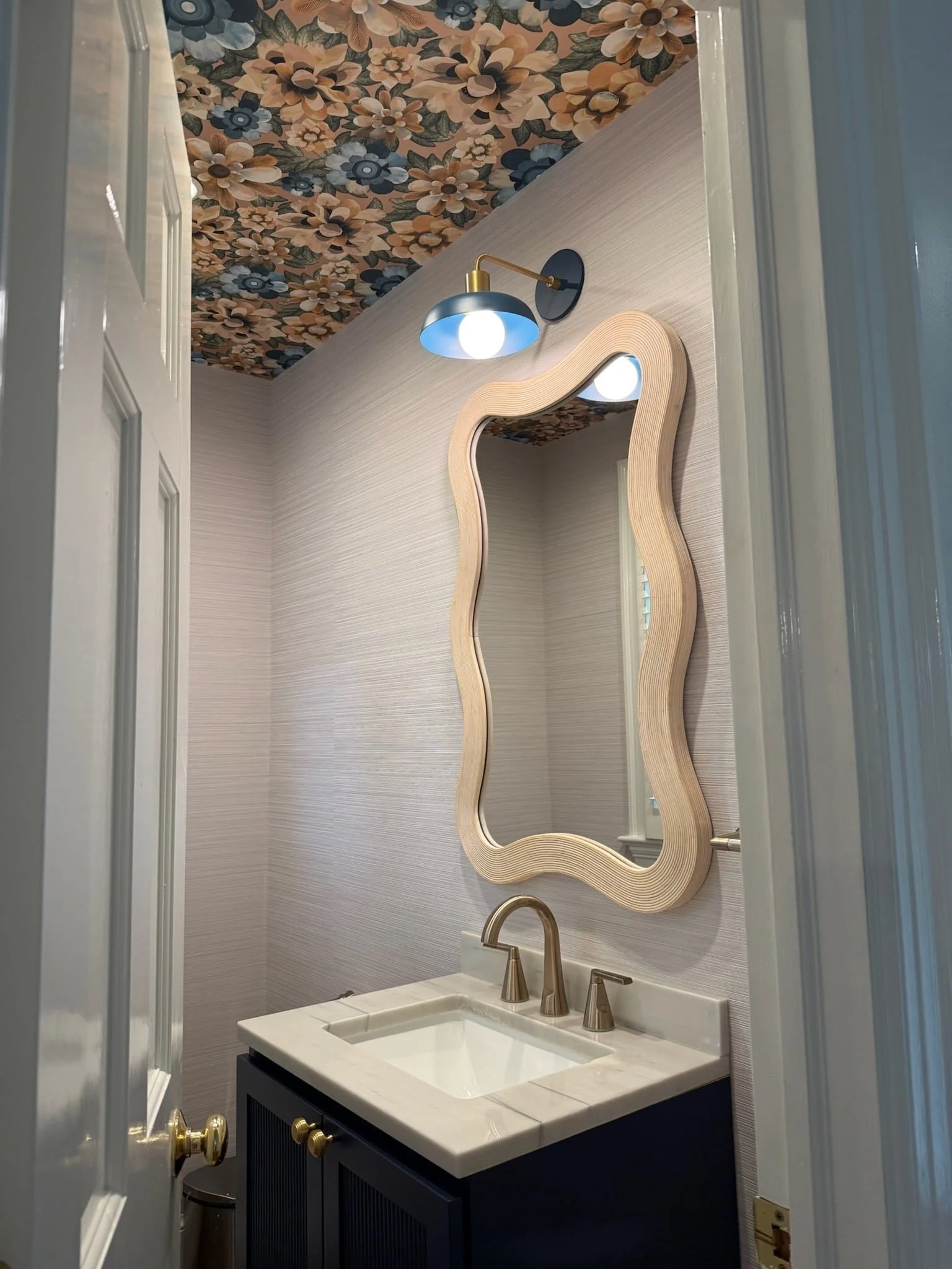 Sharing another fun powder room &mdash; this one in Chevy Chase mixes textured vinyl wallpaper for durability with a bold floral ceiling paper, sculptural mirror, and blue sconce. 

Sometimes all it takes is one bold detail to make a room memorable. 