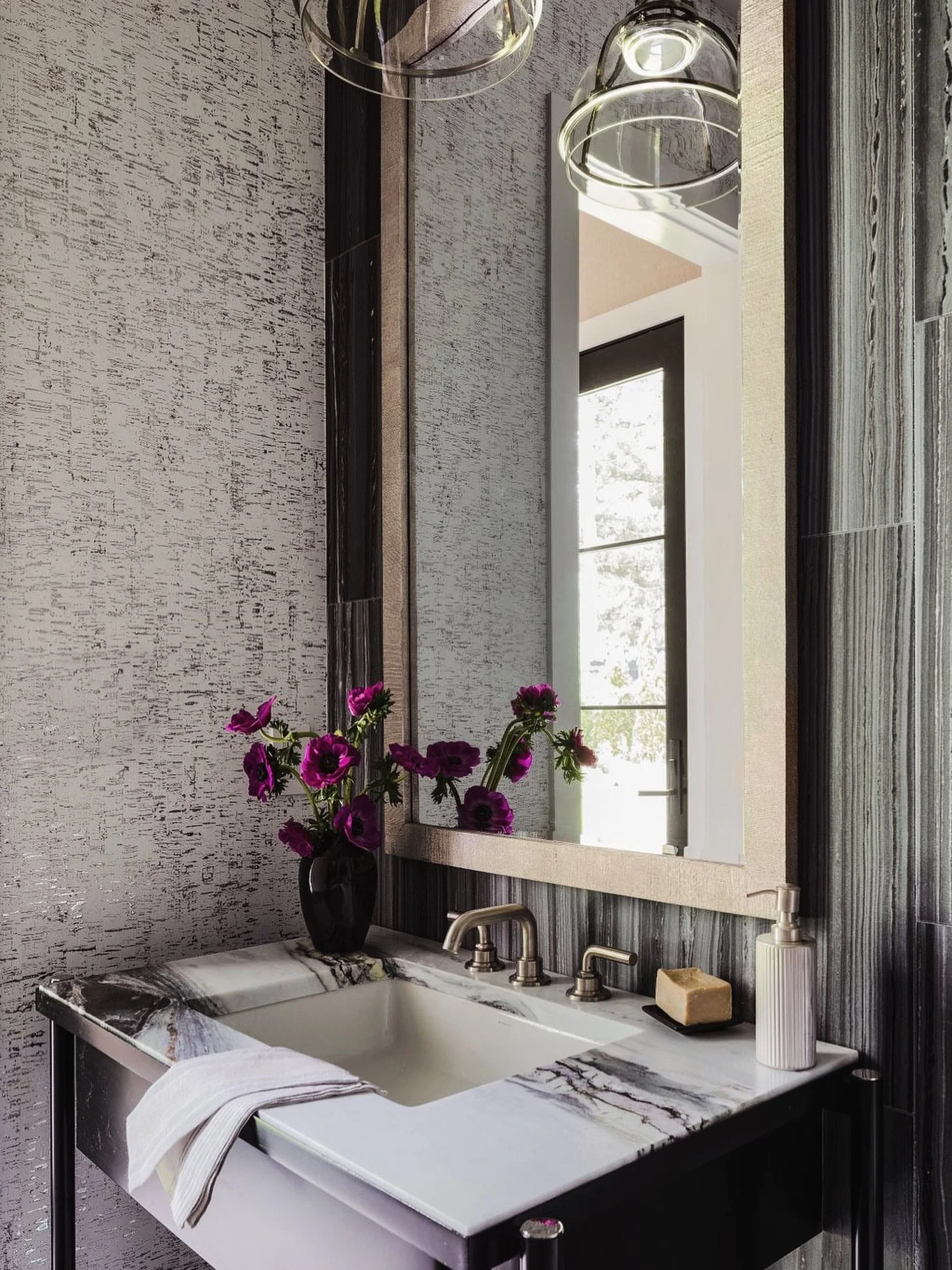Sometimes a powder room doesn&rsquo;t need color to make an impact.

The contrast of dramatic stone, layered texture, reflective finishes, and oversized lighting did all the work here.

#powderroomdesign #bathroomideas #inspiredlivabledesigns
