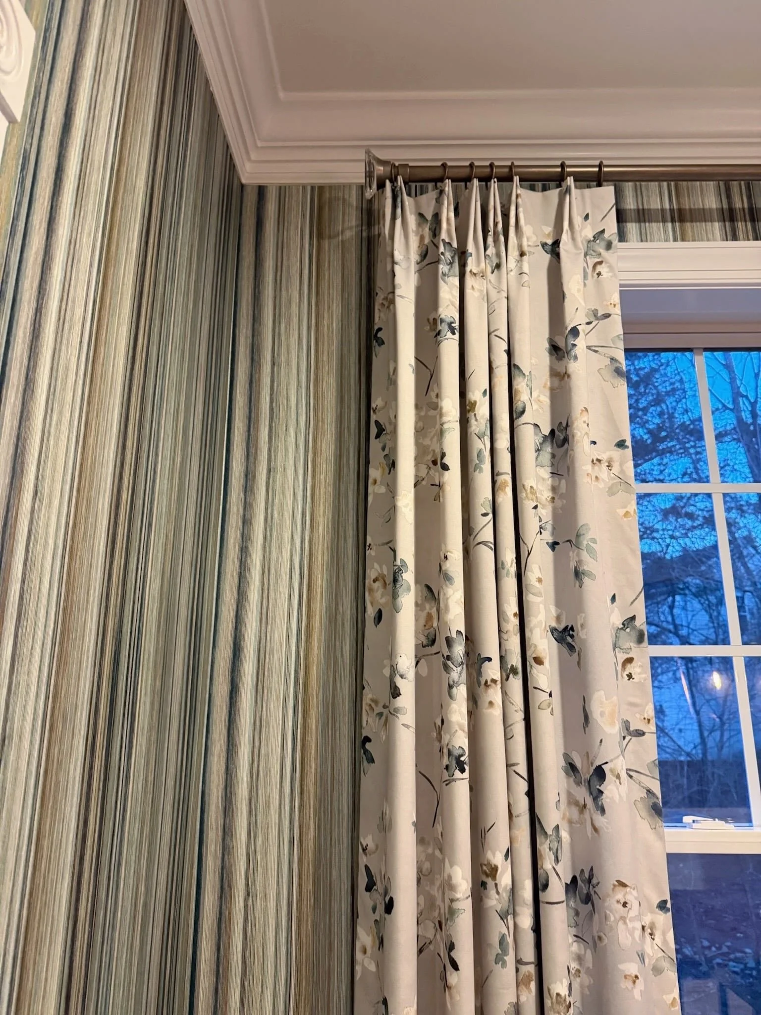 Mixing patterns works best when they have a reason to work together. 

Here, the vertical movement of the striped wallcovering creates a beautiful backdrop for the softer, more organic floral on the drapery.

Both are from Romo, and the shared palett