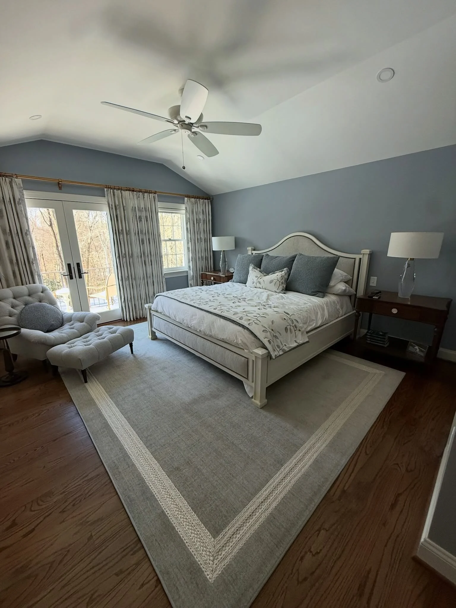 In this Fairfax, VA primary suite, we brought together soft blue-gray tones, layered fabrics, tailored furnishings, and warm wood accents to create a comfortable, personal space.

One of my favorite details is the cozy chair and ottoman tucked beside