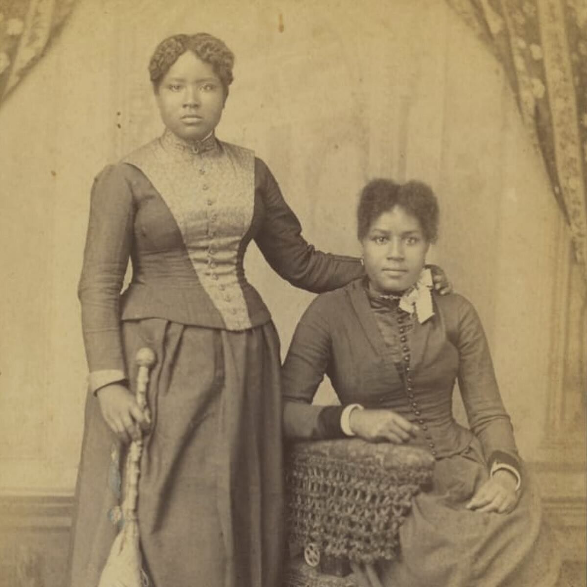 c 1885, studio portrait of two young women, one seated, one standing while embracing the other and holding a parasol, taken in Seguin, Texas &mdash;The Henry Ford Collection