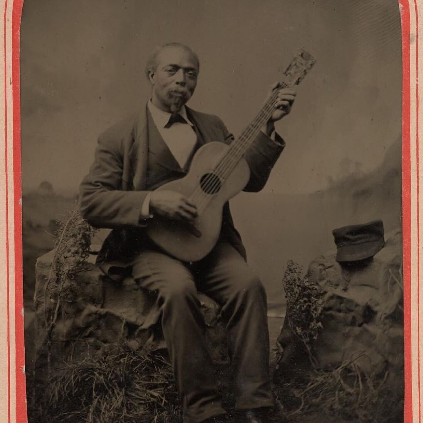 c 1885, decorated studio tintype of a man holding a guitar, with hap resting on adjacent studio prop &mdash;Yale University Library, Digital Collections