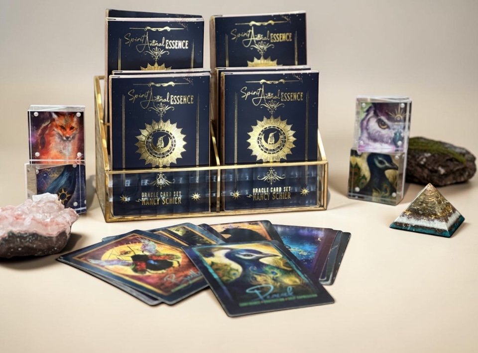 Set of oracle cards with mystical and zodiac-themed designs, displayed alongside decorative rocks and stones, in a spiritual or fortune-telling setup.
