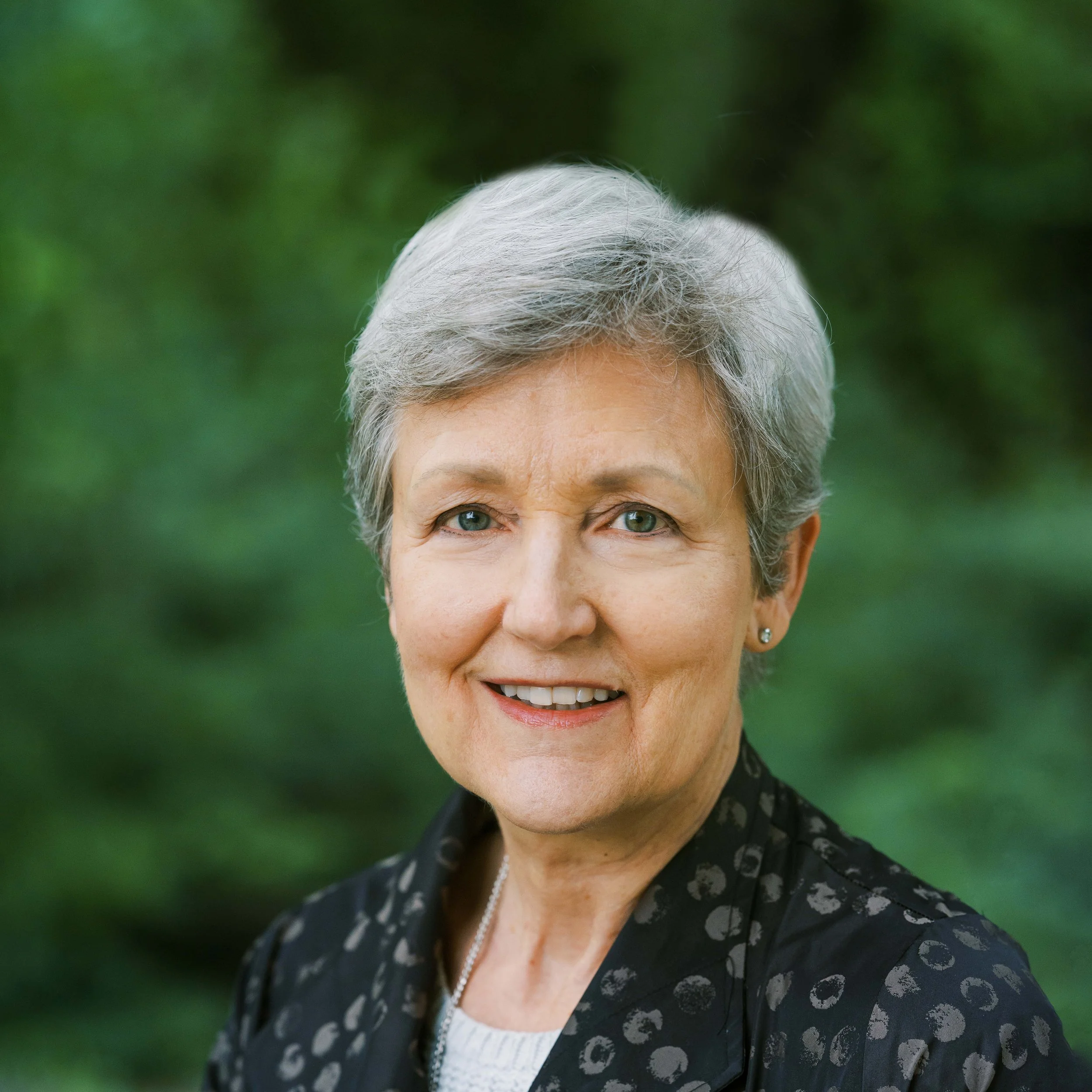 Elderly woman with short gray hair smiling outdoors