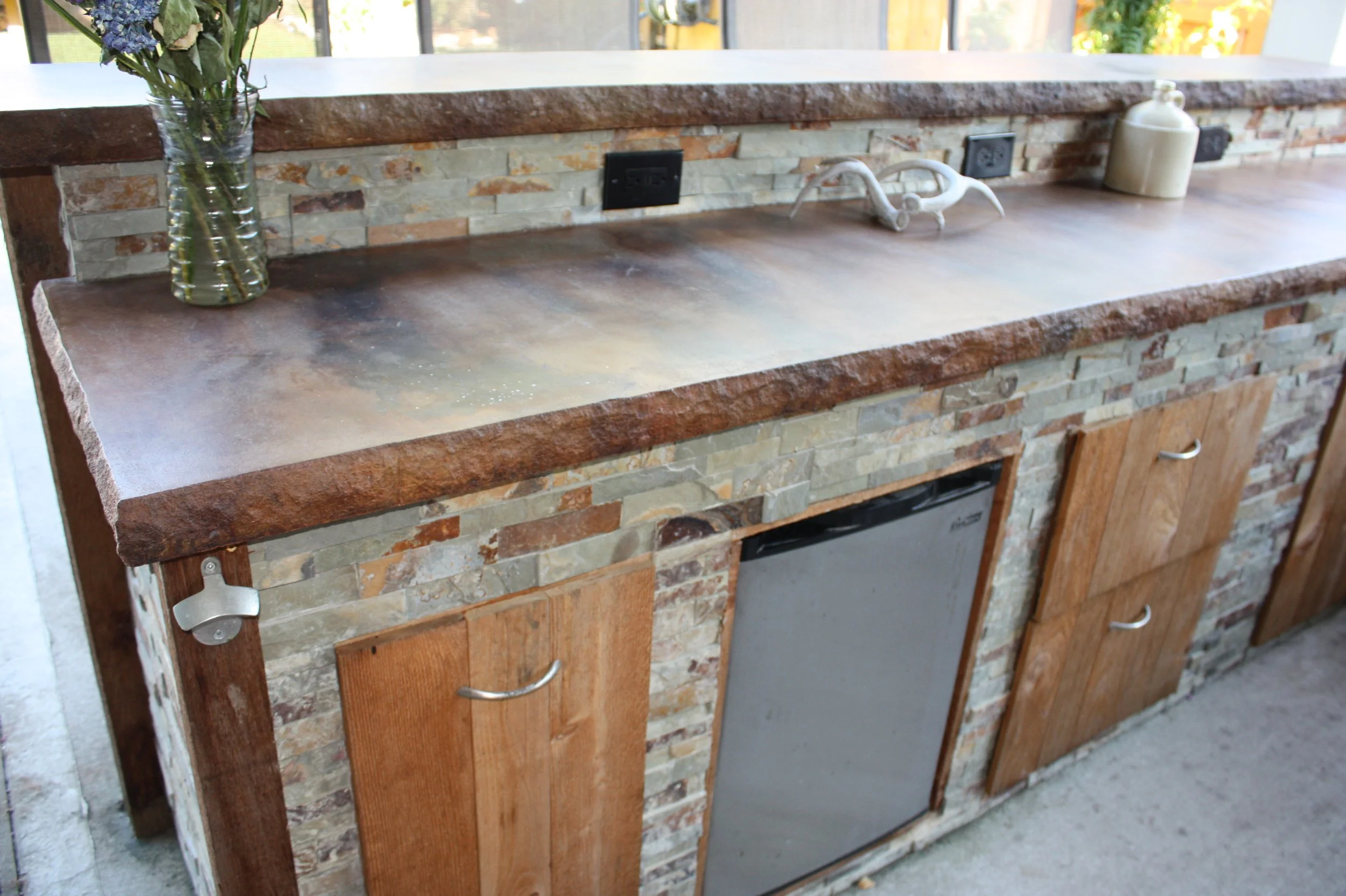 We do not miss details! This kitchen has several built in outlets, a built in trash can, a mini fridge, and even a bottle opener. We build with utility in mind.