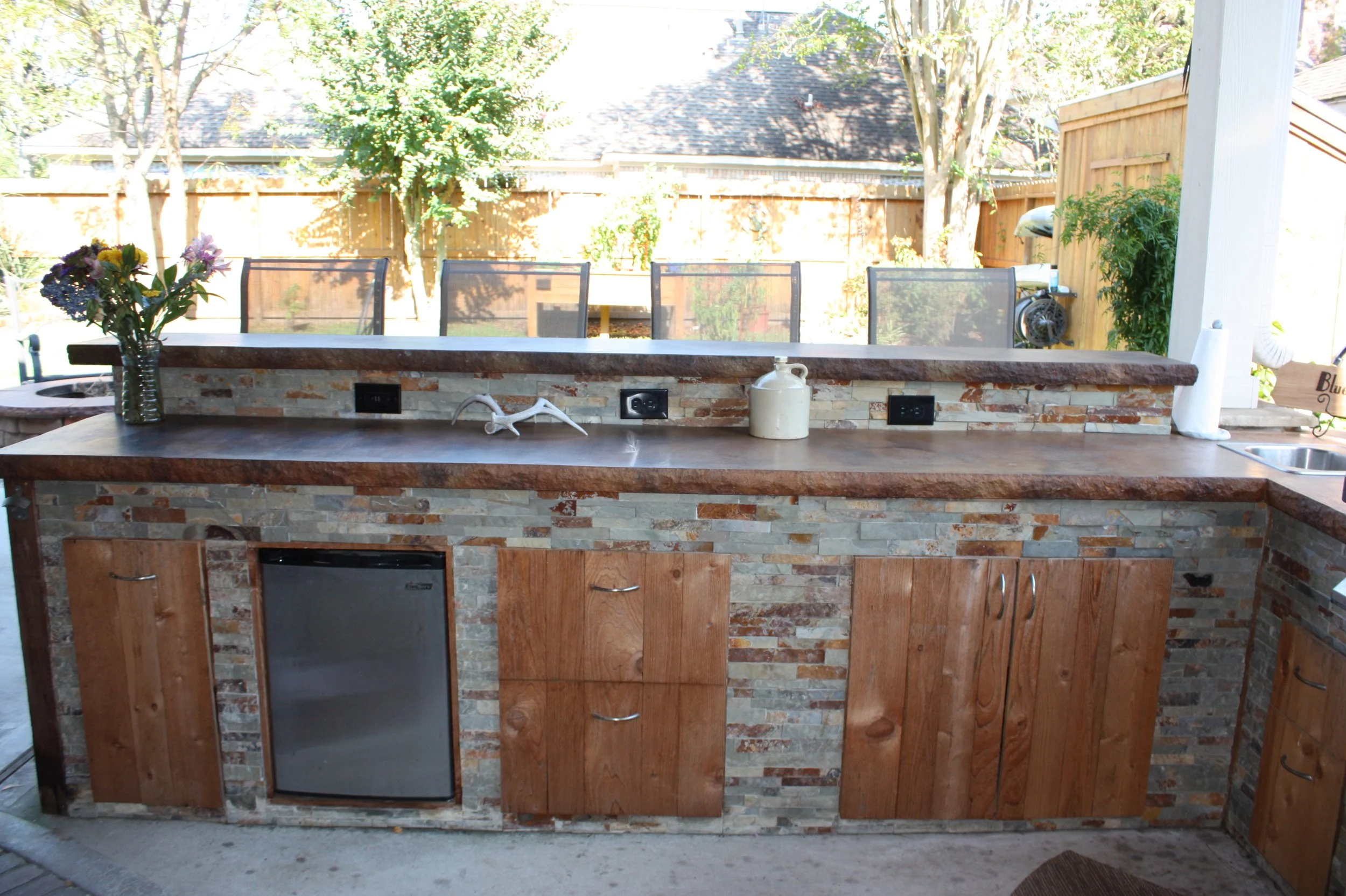This kitchen is built with a beautiful multicolor natural stone, cedar cabinets and drawers, and a poured in place concrete countertop.