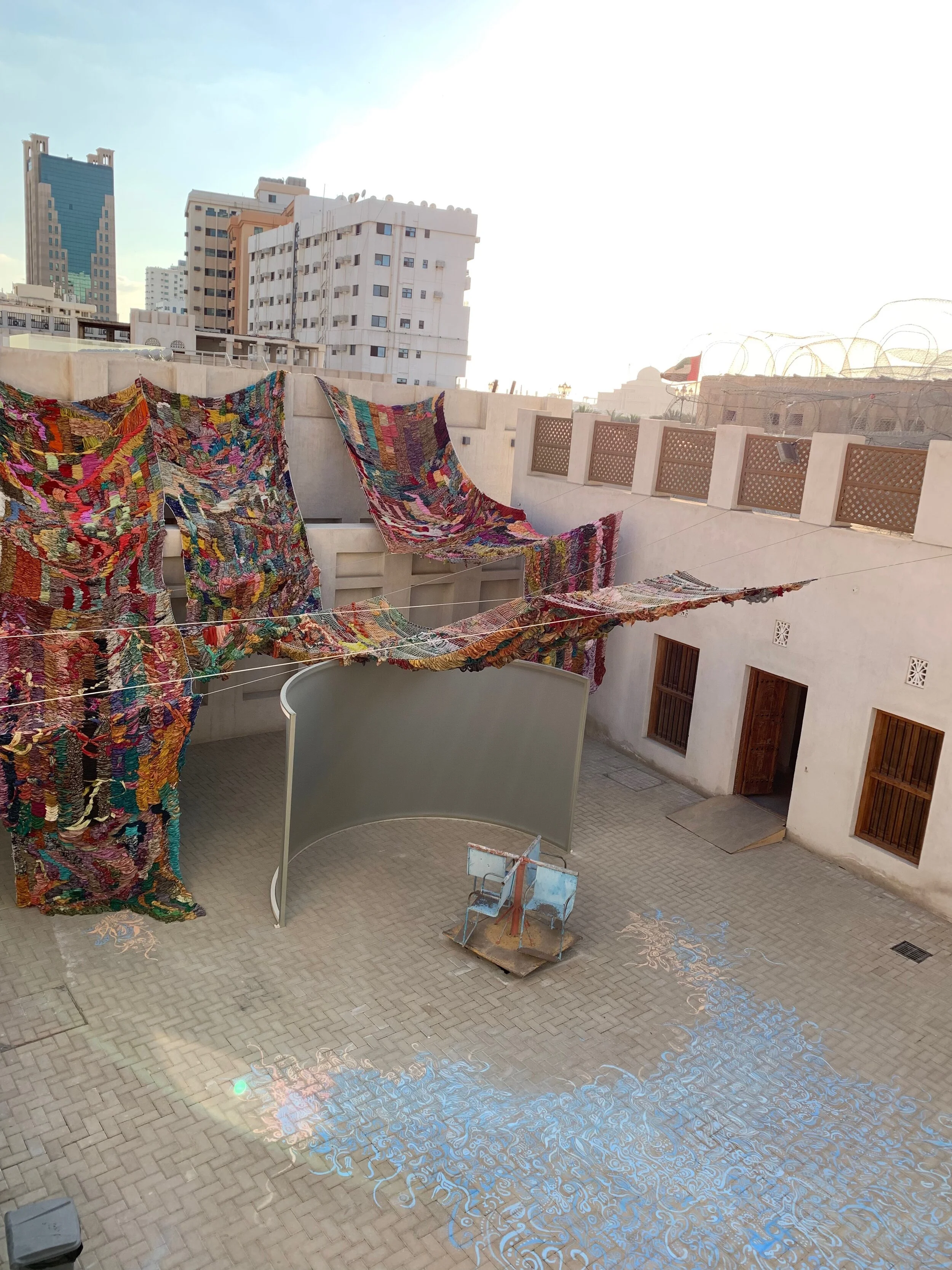 "Imperfect Isometry," 2019, videos of border walls  (Jerusalem/Palestine, US/Mexico) and prison wall, vintage sari tapestry, chalk drawing, spinning found Kalba merrygoround, dimensions variable 