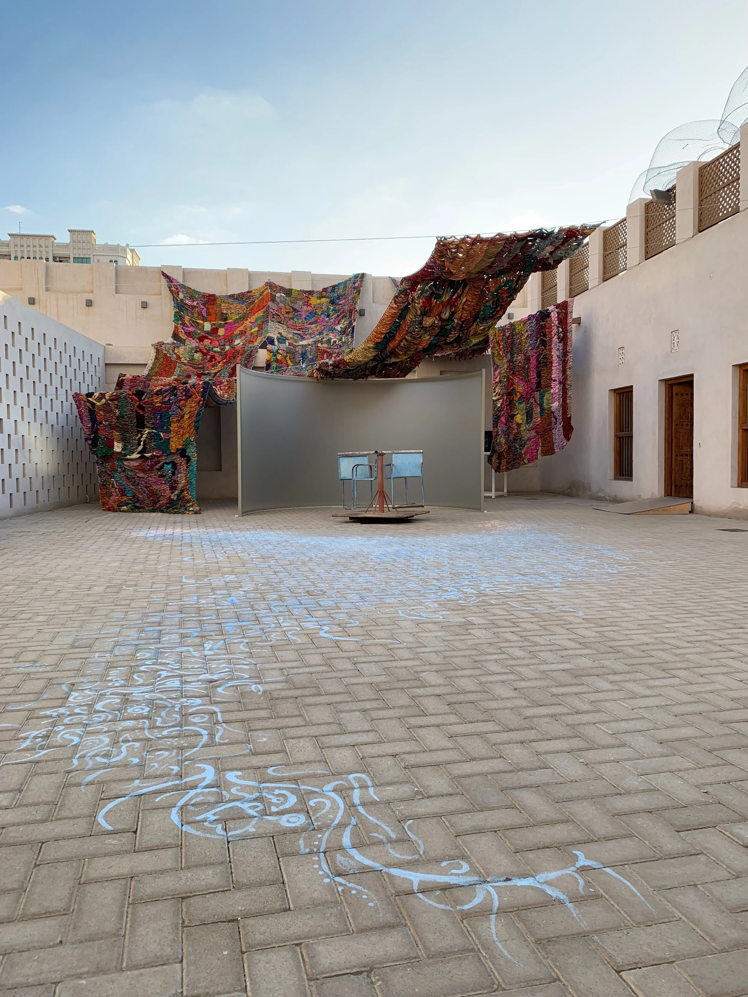 "Imperfect Isometry," 2019, videos of border walls  (Jerusalem/Palestine, US/Mexico) and prison wall, vintage sari tapestry, chalk drawing, spinning found Kalba merrygoround, dimensions variable 