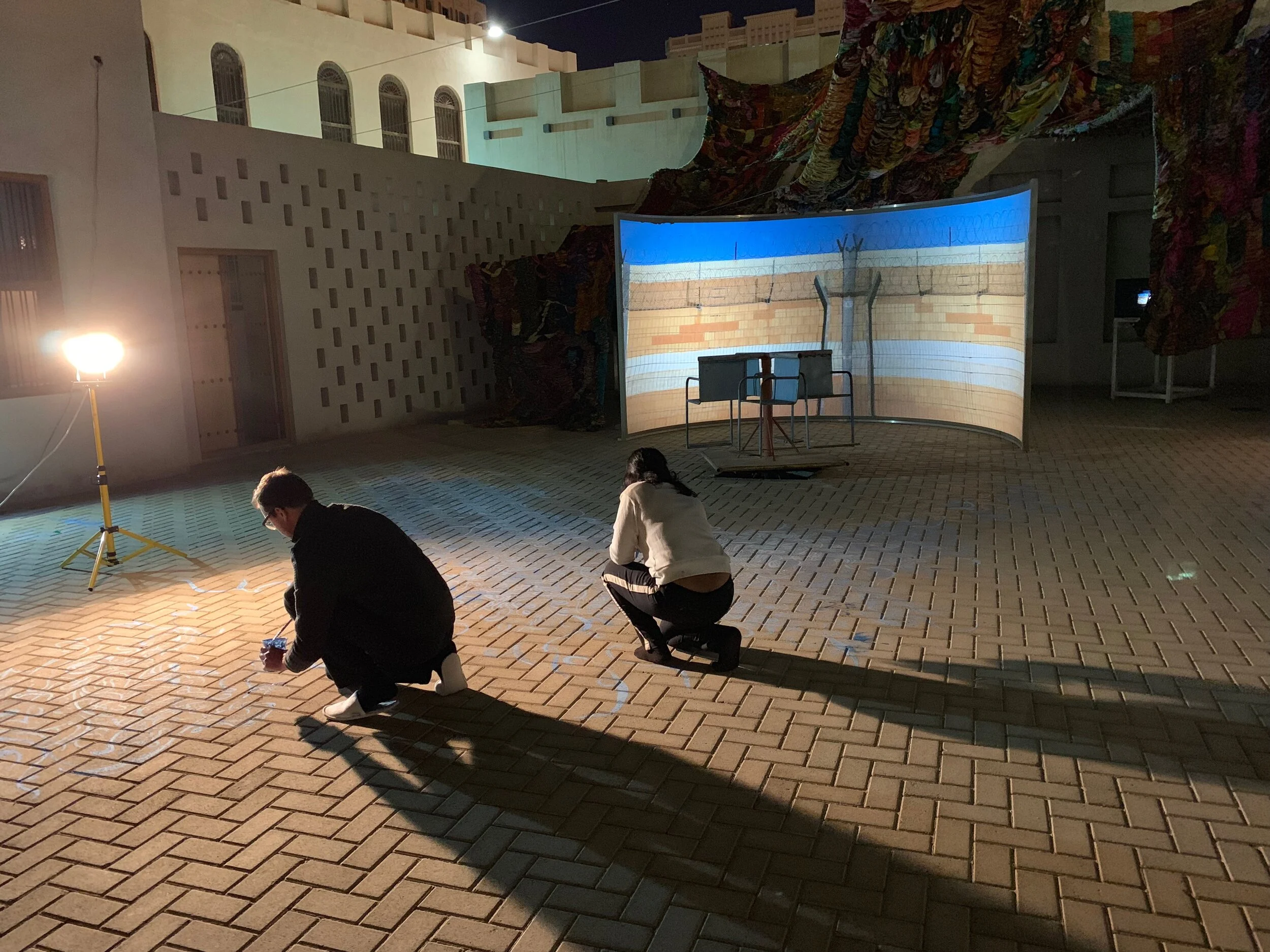 process photos, for "Imperfect Isometry," 2019, videos of border walls  (Jerusalem/Palestine, US/Mexico) and prison wall, vintage sari tapestry, chalk drawing, spinning found Kalba merrygoround, dimensions variable 
