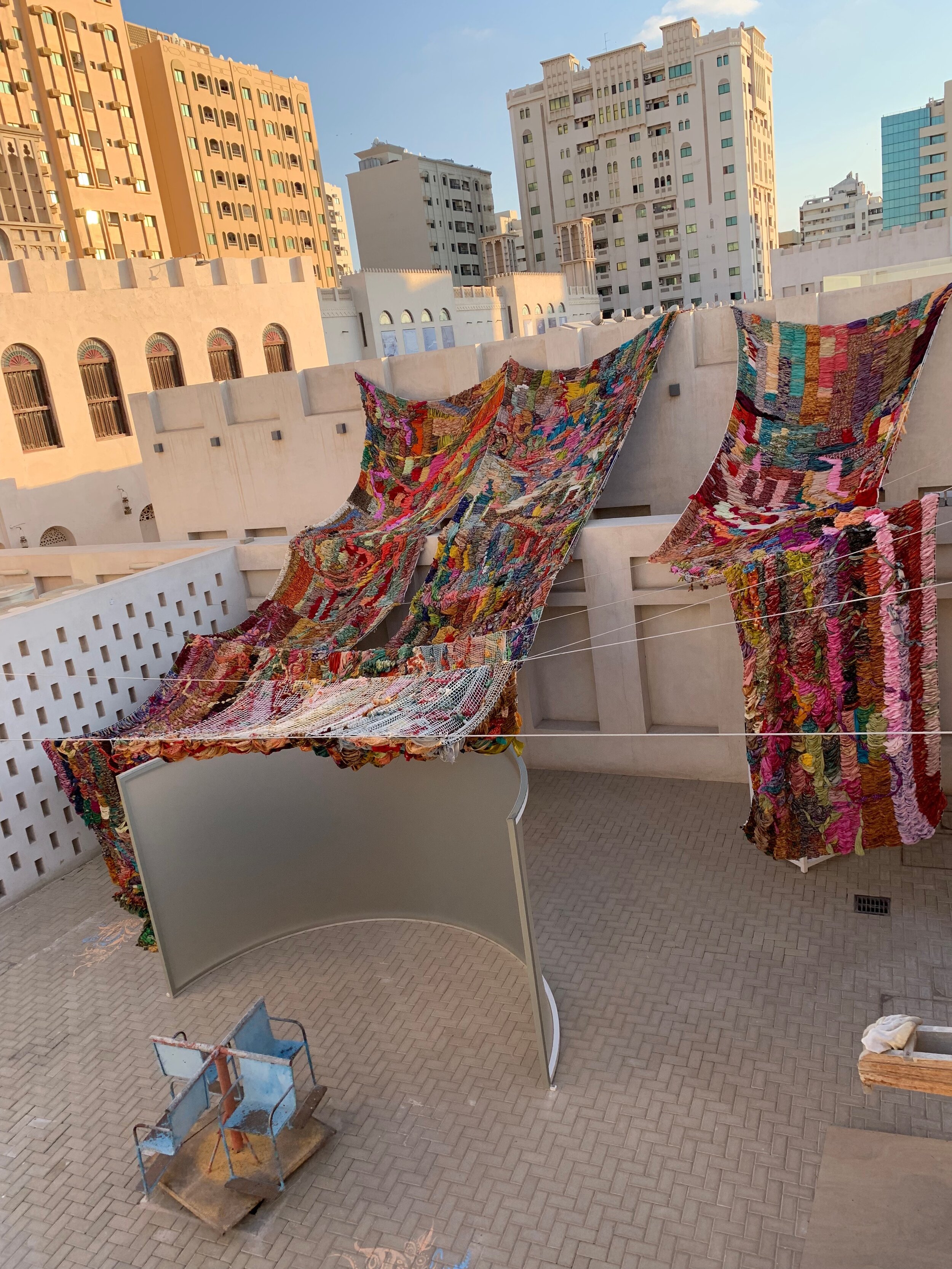 "Imperfect Isometry," 2019, videos of border walls  (Jerusalem/Palestine, US/Mexico) and prison wall, vintage sari tapestry, chalk drawing, spinning found Kalba merrygoround, dimensions variable 