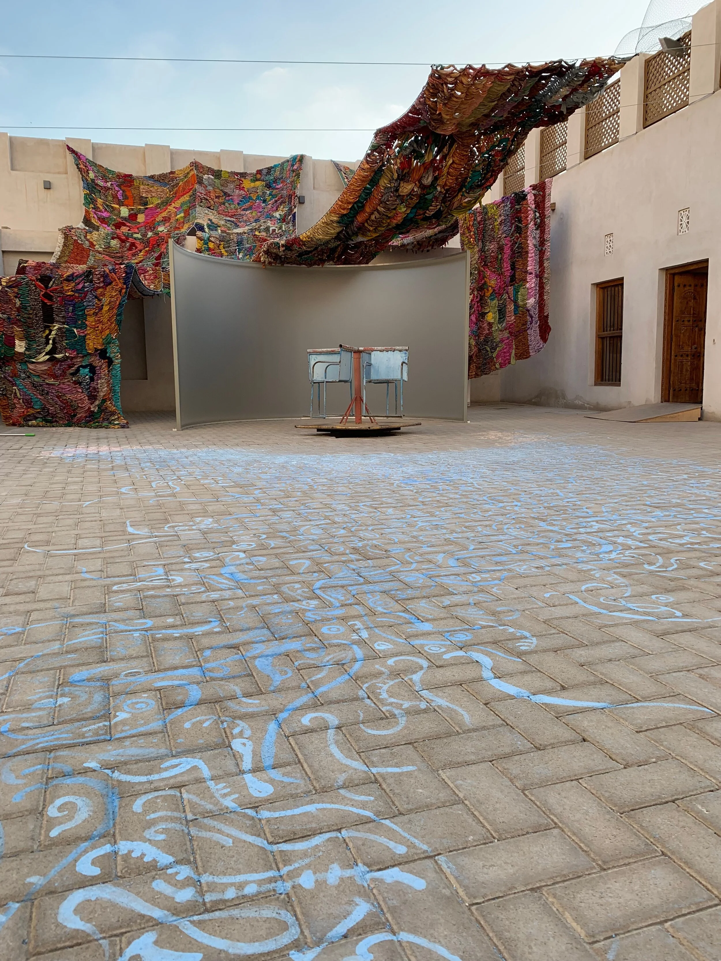 "Imperfect Isometry," 2019, videos of border walls  (Jerusalem/Palestine, US/Mexico) and prison wall, vintage sari tapestry, chalk drawing, spinning found Kalba merrygoround, dimensions variable 