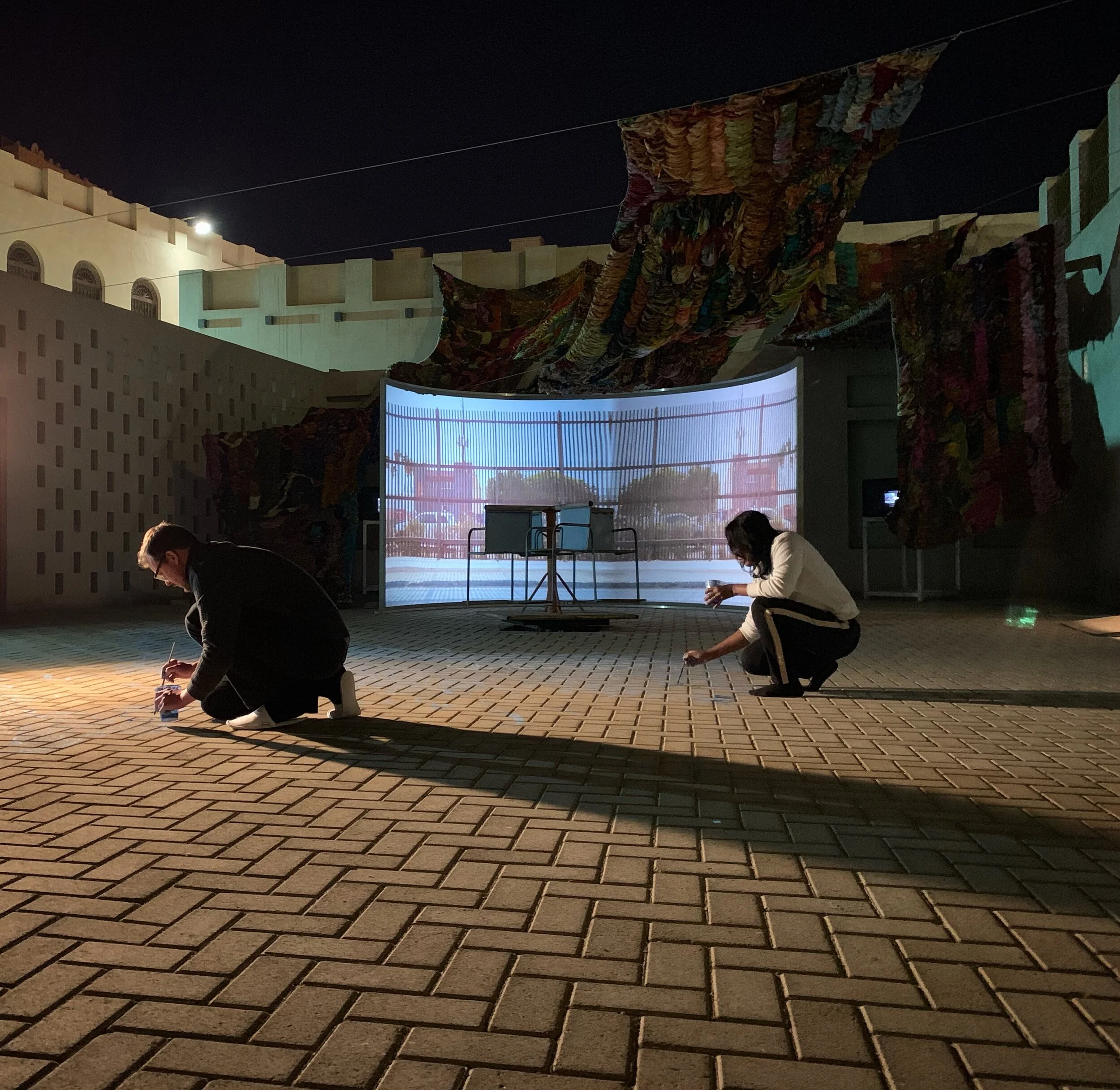 process photos, for "Imperfect Isometry," 2019, videos of border walls  (Jerusalem/Palestine, US/Mexico) and prison wall, vintage sari tapestry, chalk drawing, spinning found Kalba merrygoround, dimensions variable 