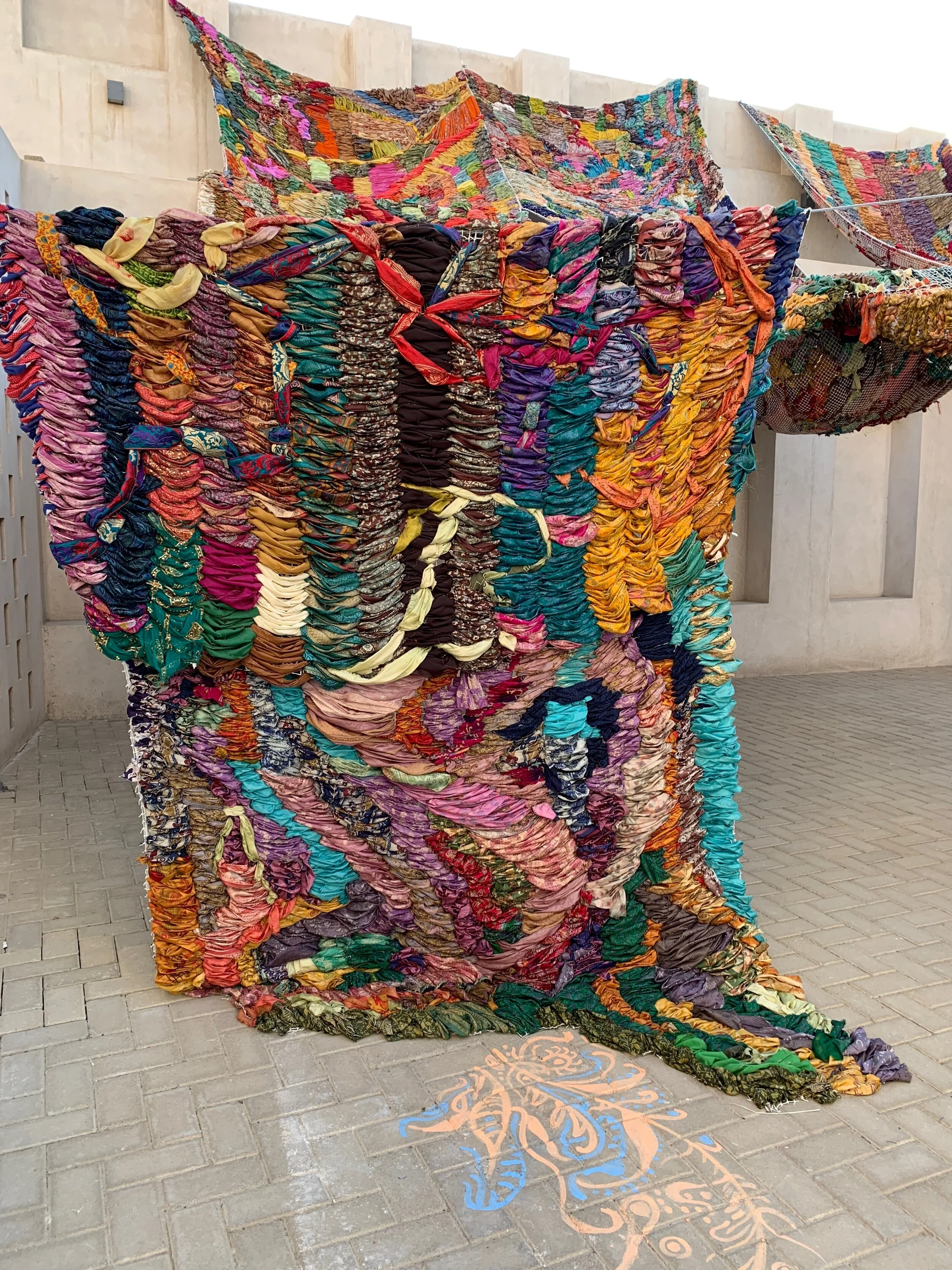 "Imperfect Isometry," 2019, videos of border walls  (Jerusalem/Palestine, US/Mexico) and prison wall, vintage sari tapestry, chalk drawing, spinning found Kalba merrygoround, dimensions variable 