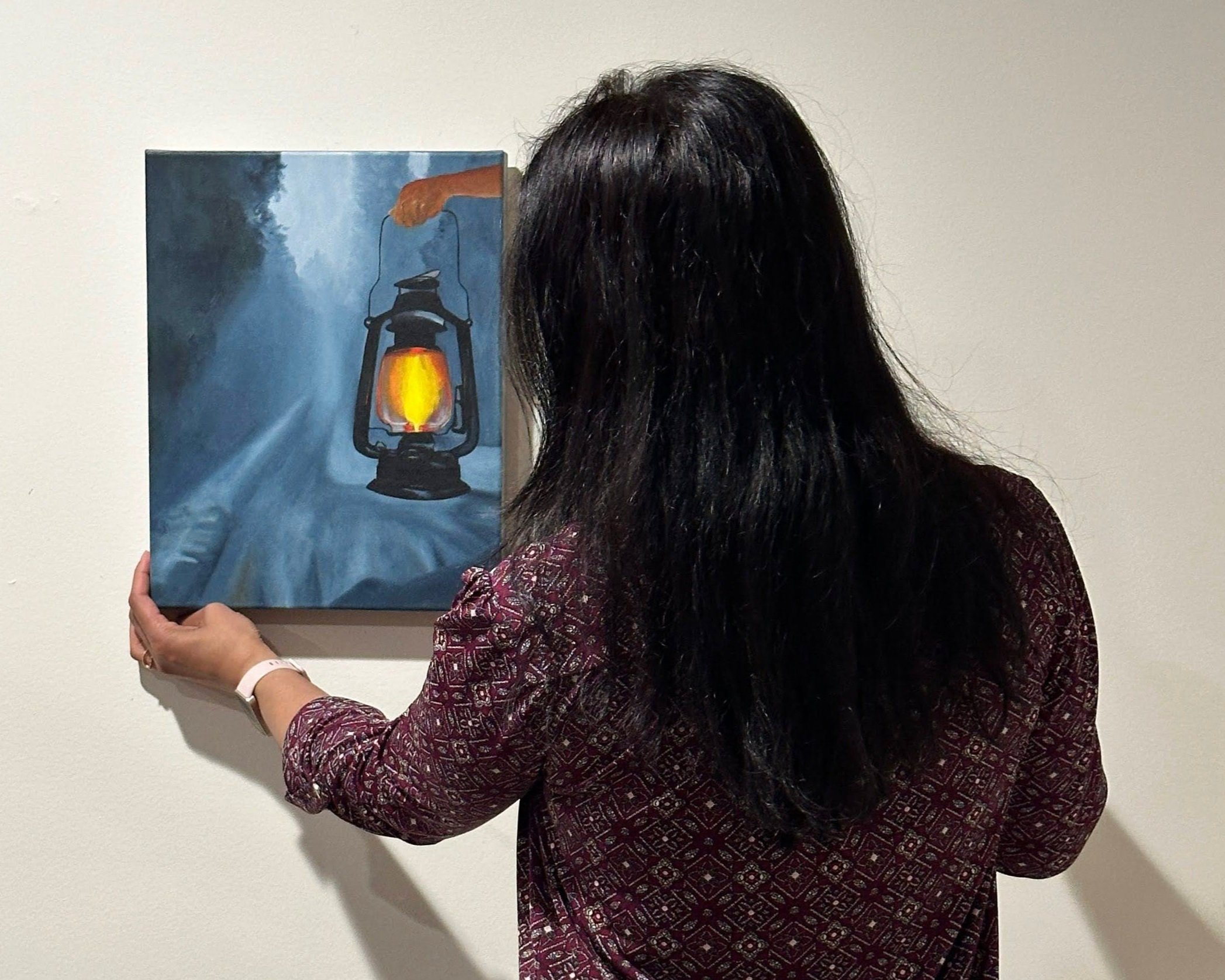 Person holding a painting of a hand with a lantern. Be the light around you!