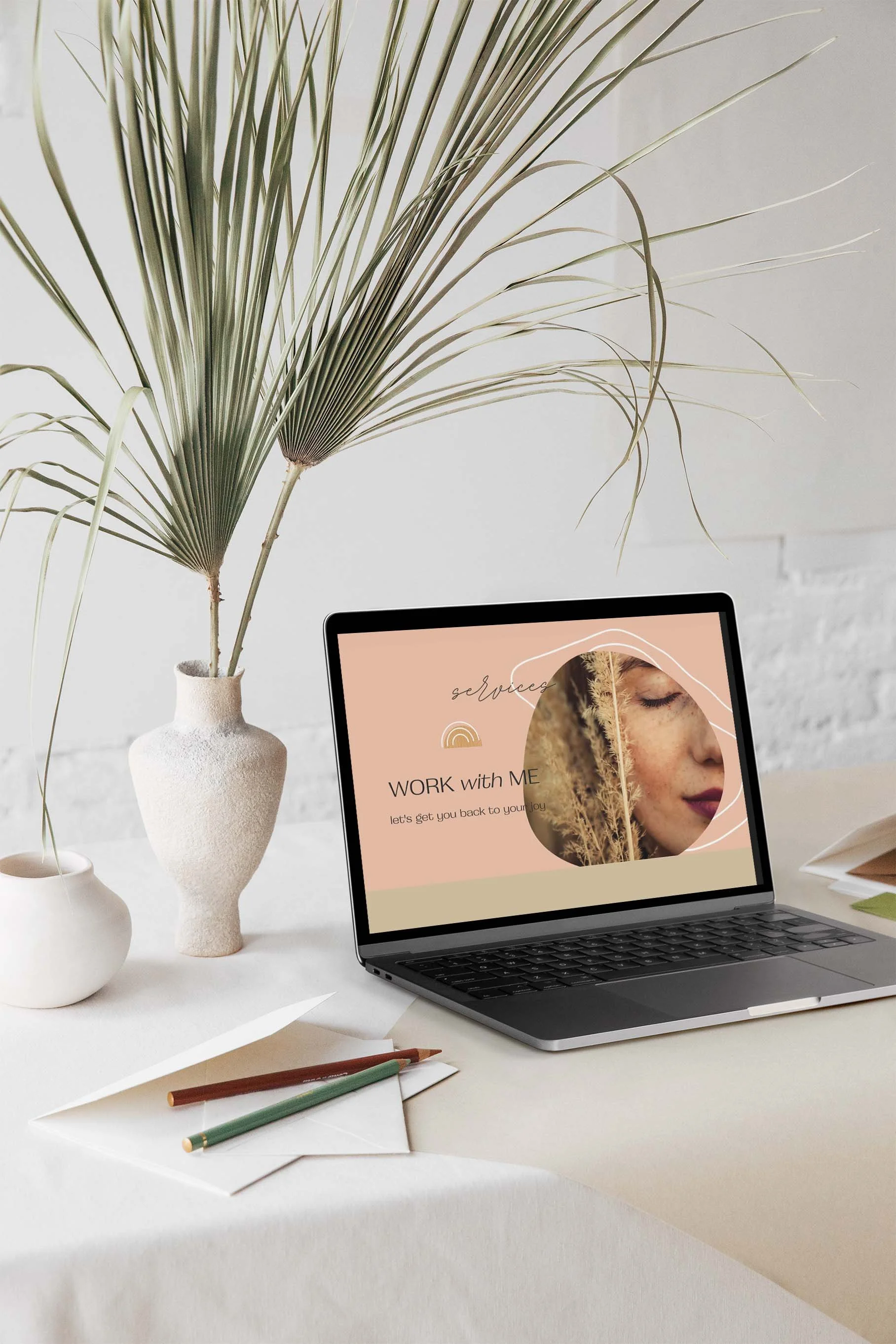 Laptop on table with plant and stationery, showing "Work with Me" screen text.