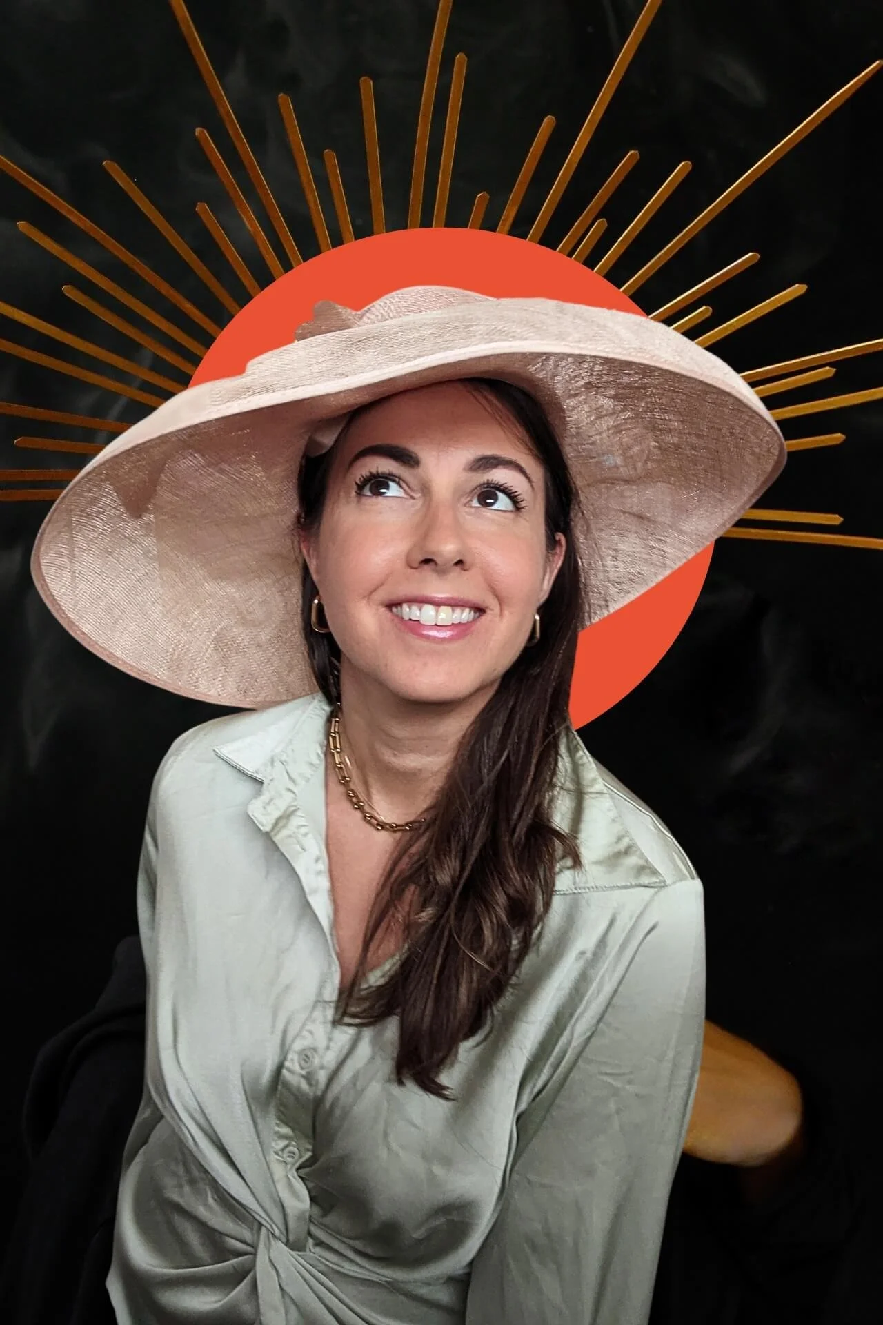 A woman wearing a wide-brimmed beige hat with decorative gold accents, smiling and looking upward, with a stylized orange sun and gold rays graphic behind her.