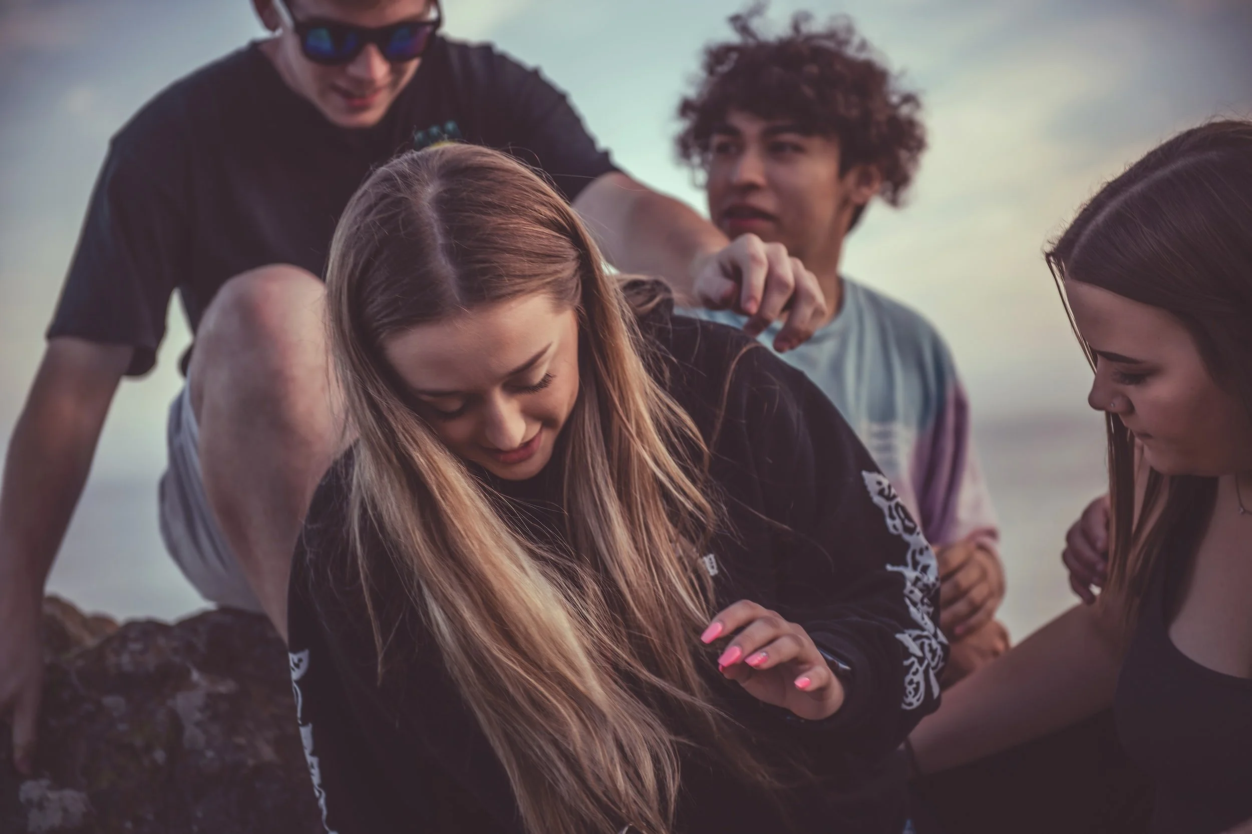 Groupe d'amis à l'extérieur lors du coucher de soleil, en train de poser pour une photo, certains souriant et d'autres pensifs. Cliché utilisé comme illustration de site de psychologie et psychothérapie.