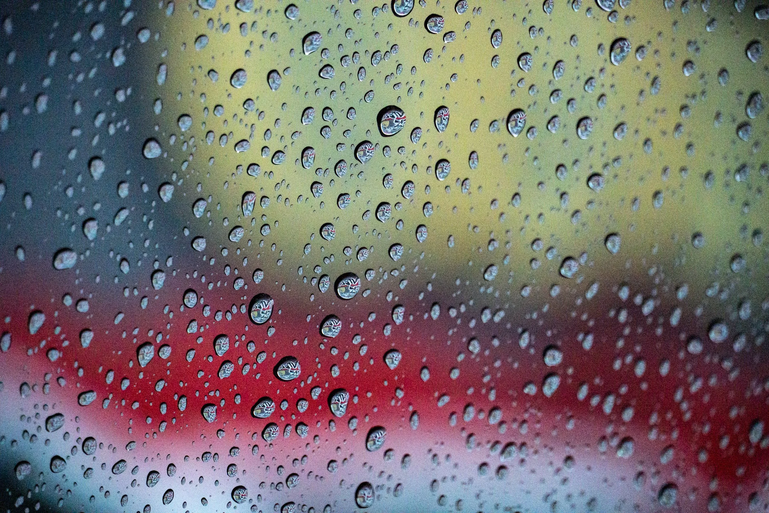 Closeup of raindrops on window in front of colorful graffiti
