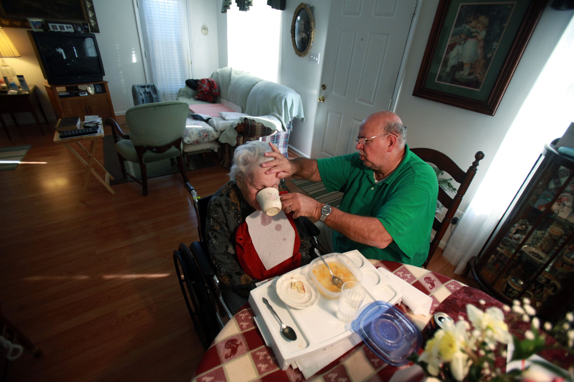  Danny holds back Elizabeth's head as he helps her eat lunch. Elizabeth's hands and feet are numb from arthritis, making it hard for her to feed herself. 