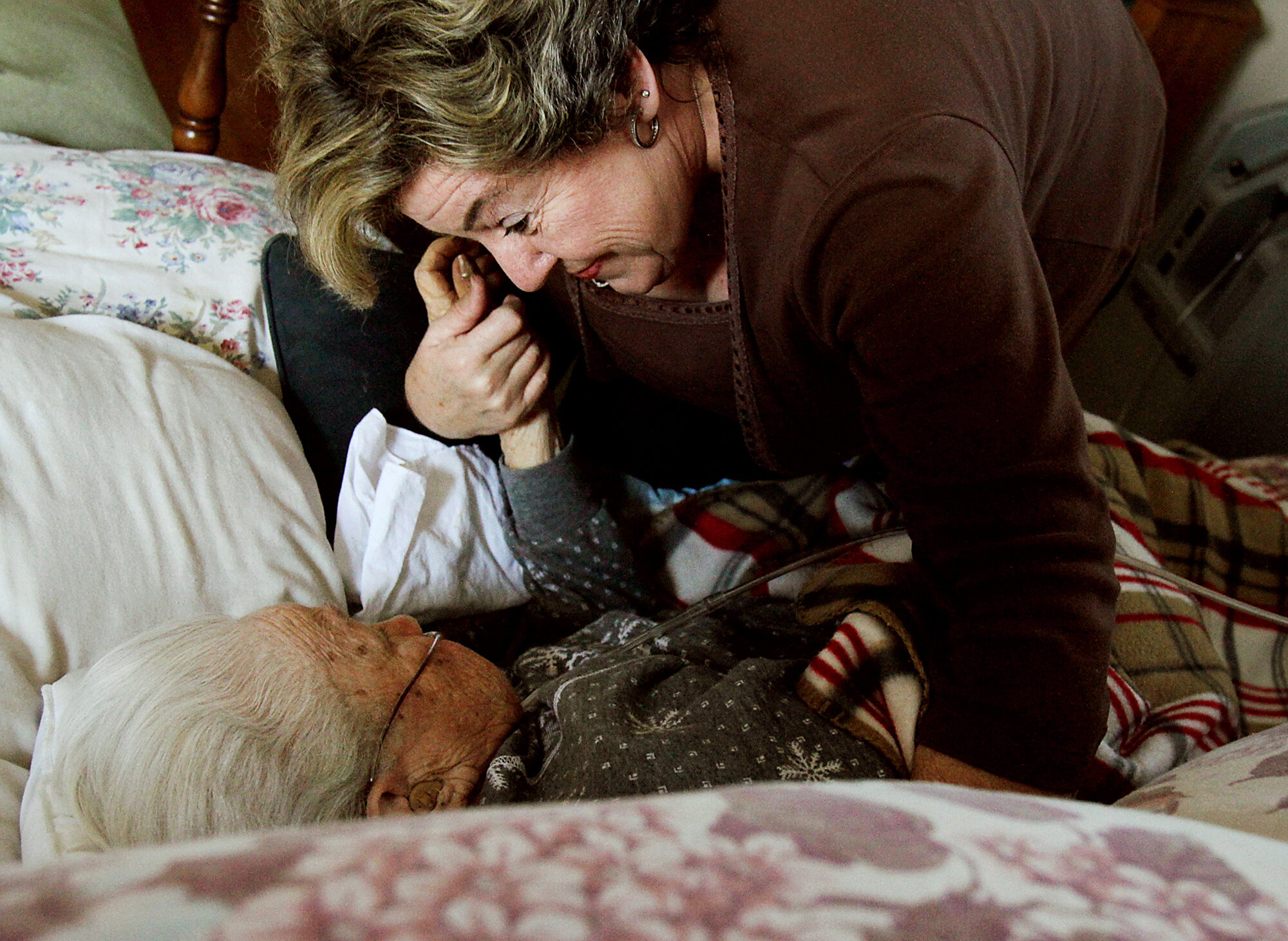  Elizabeth's daughter-in-law, Nancy, holds hands with Elizabeth during a visit.  Members of Elizabeth's family visit her at least once a week and call daily.  Their goal is to keep her comfortable during her remaining days. 